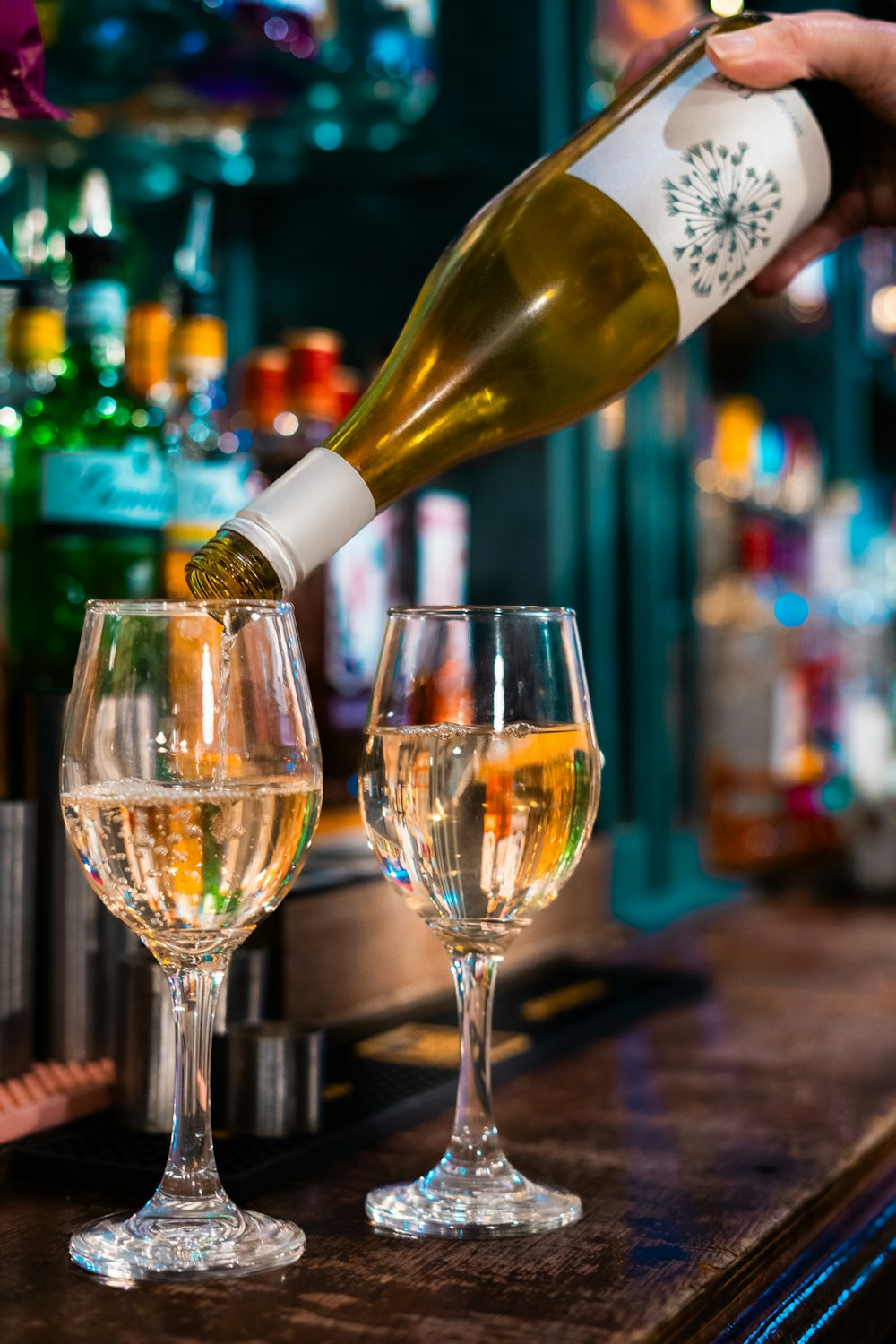 a person pouring wine into two wine glasses