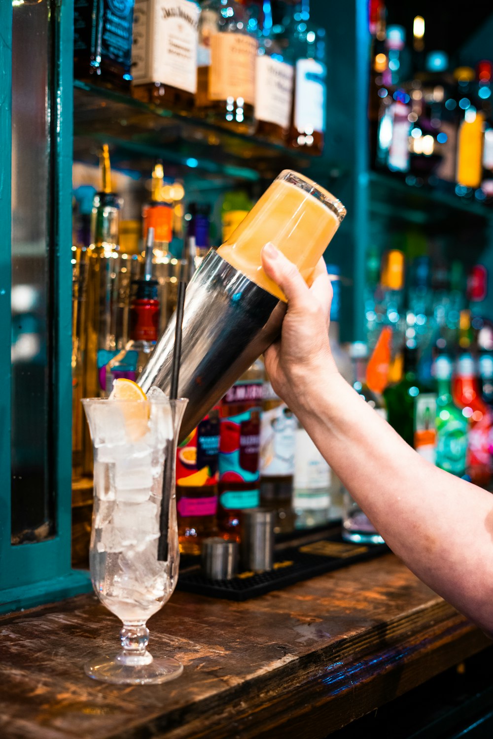 a person is pouring a drink into a glass