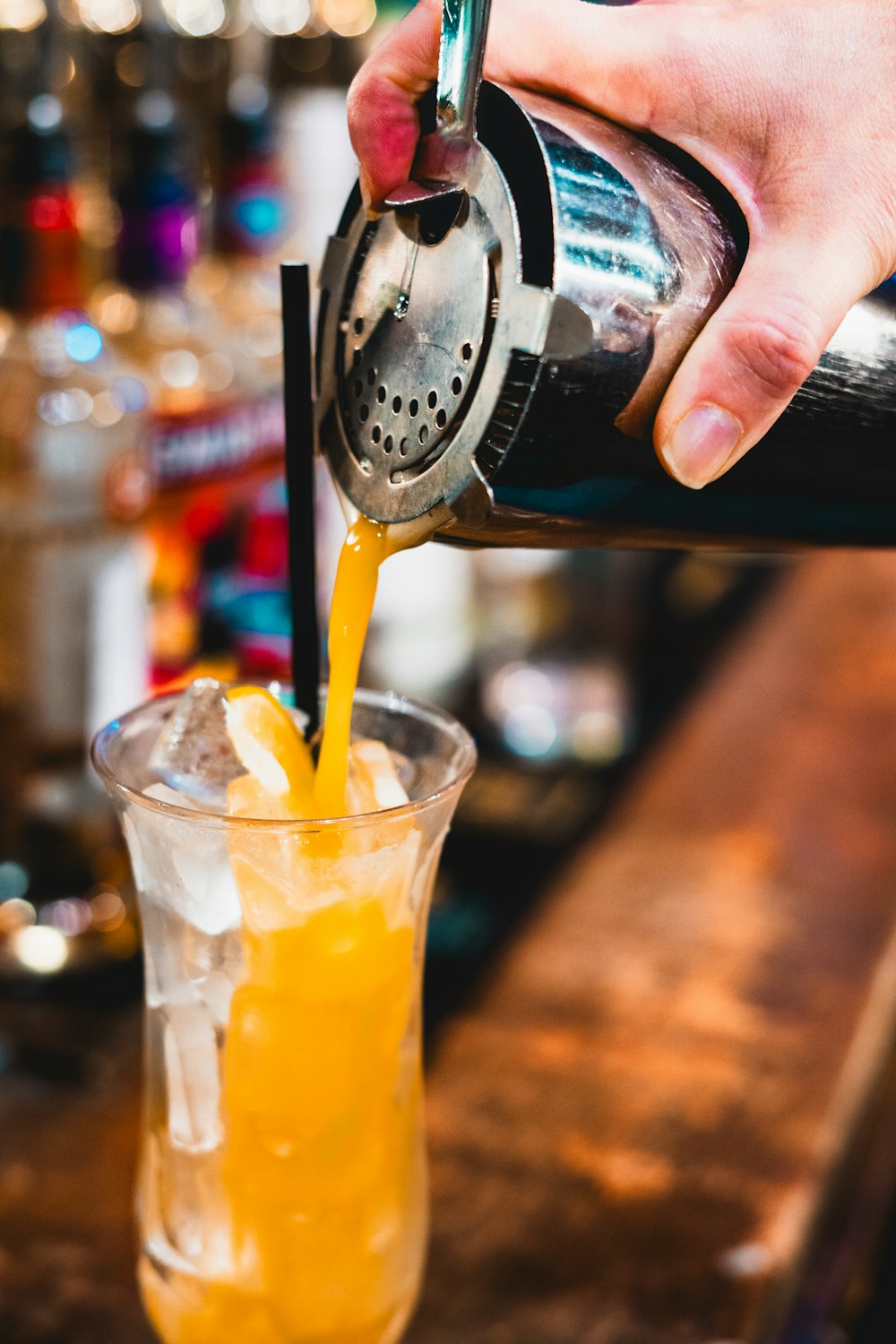 a person pouring a drink into a glass