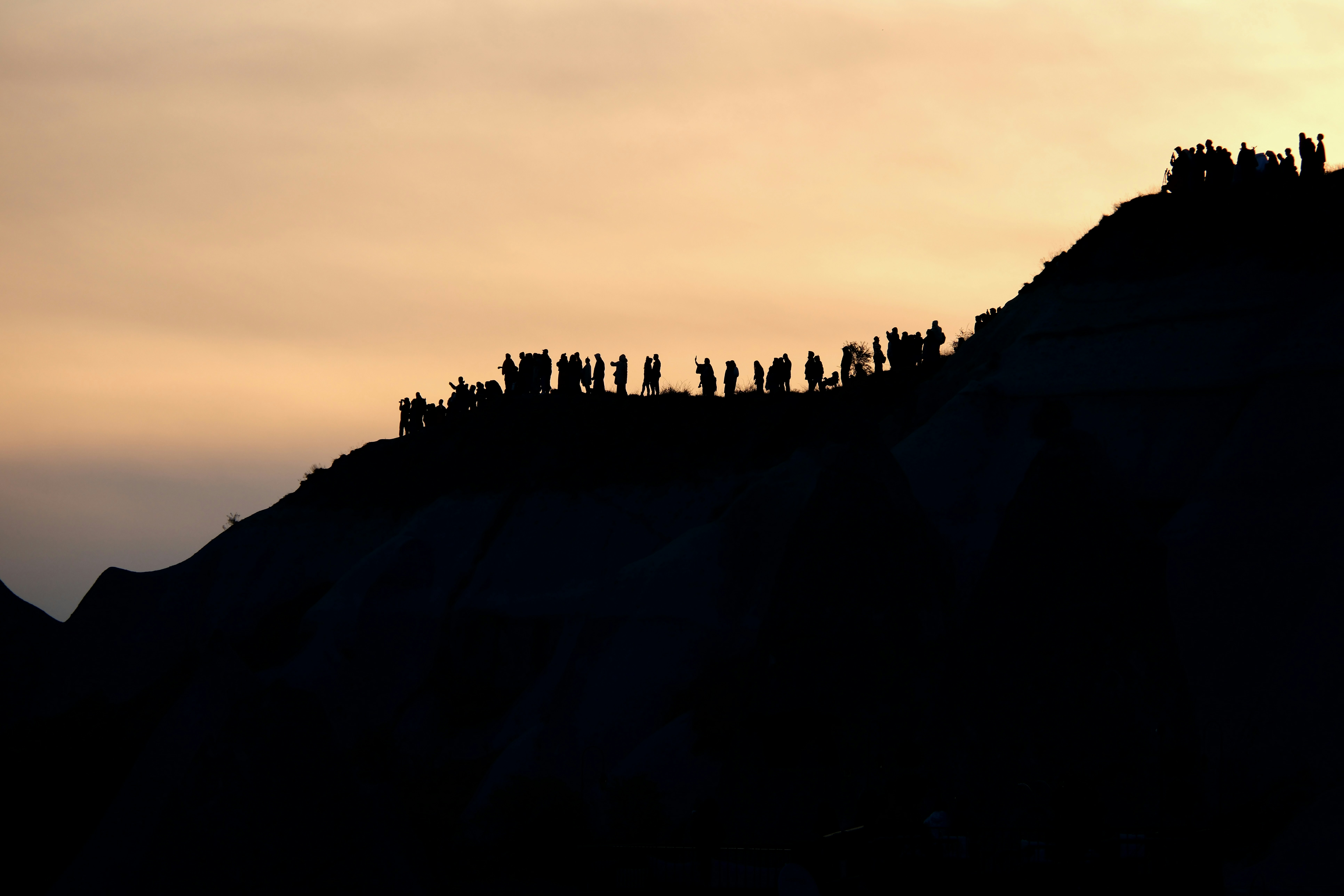 a group of people standing on top of a hill - a-group-of-people-standing-on-top-of-a-hill-EBidGH-_xOg