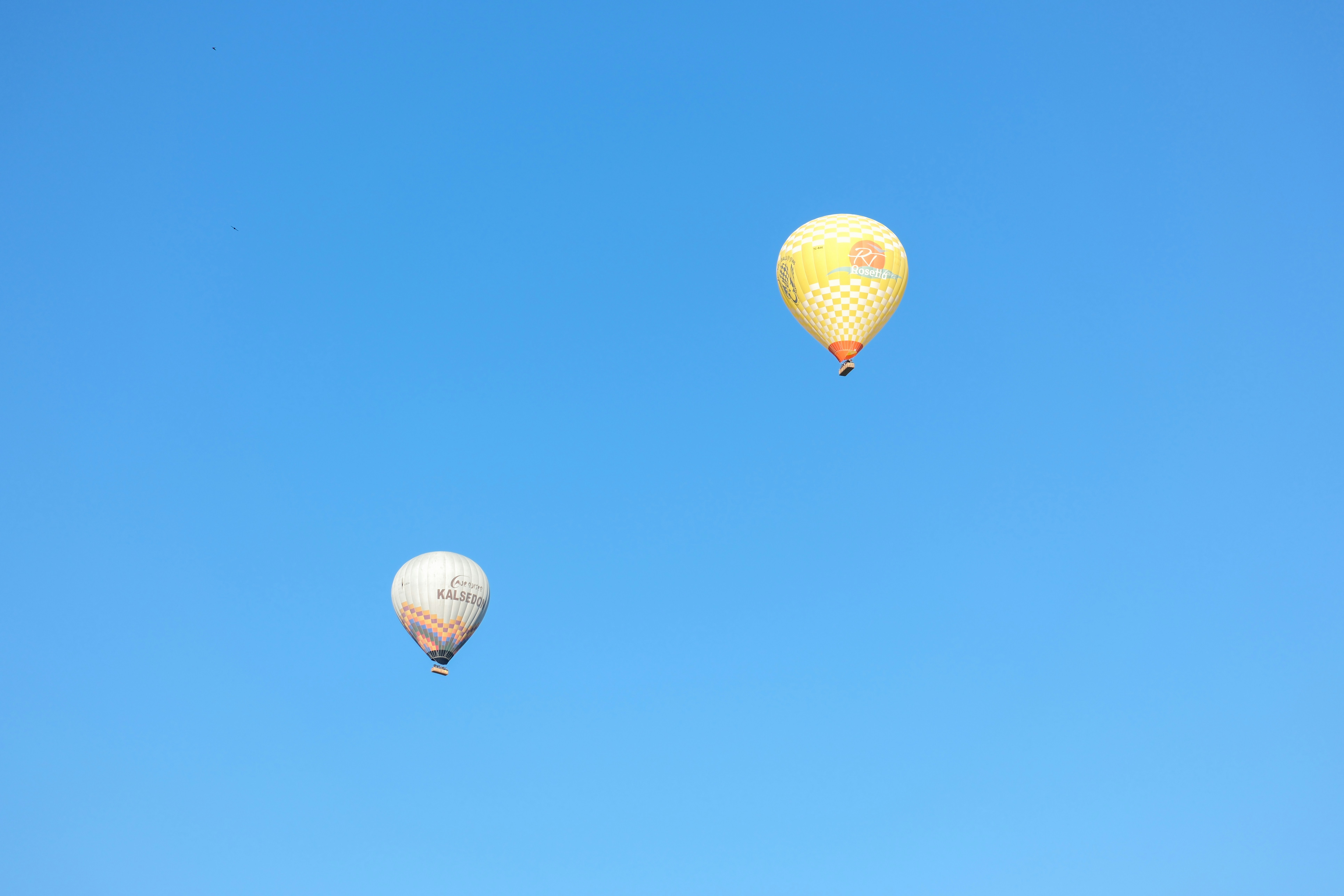 a couple of hot air balloons flying through a blue sky - a-couple-of-hot-air-balloons-flying-through-a-blue-sky-vzrAzz4jk_A