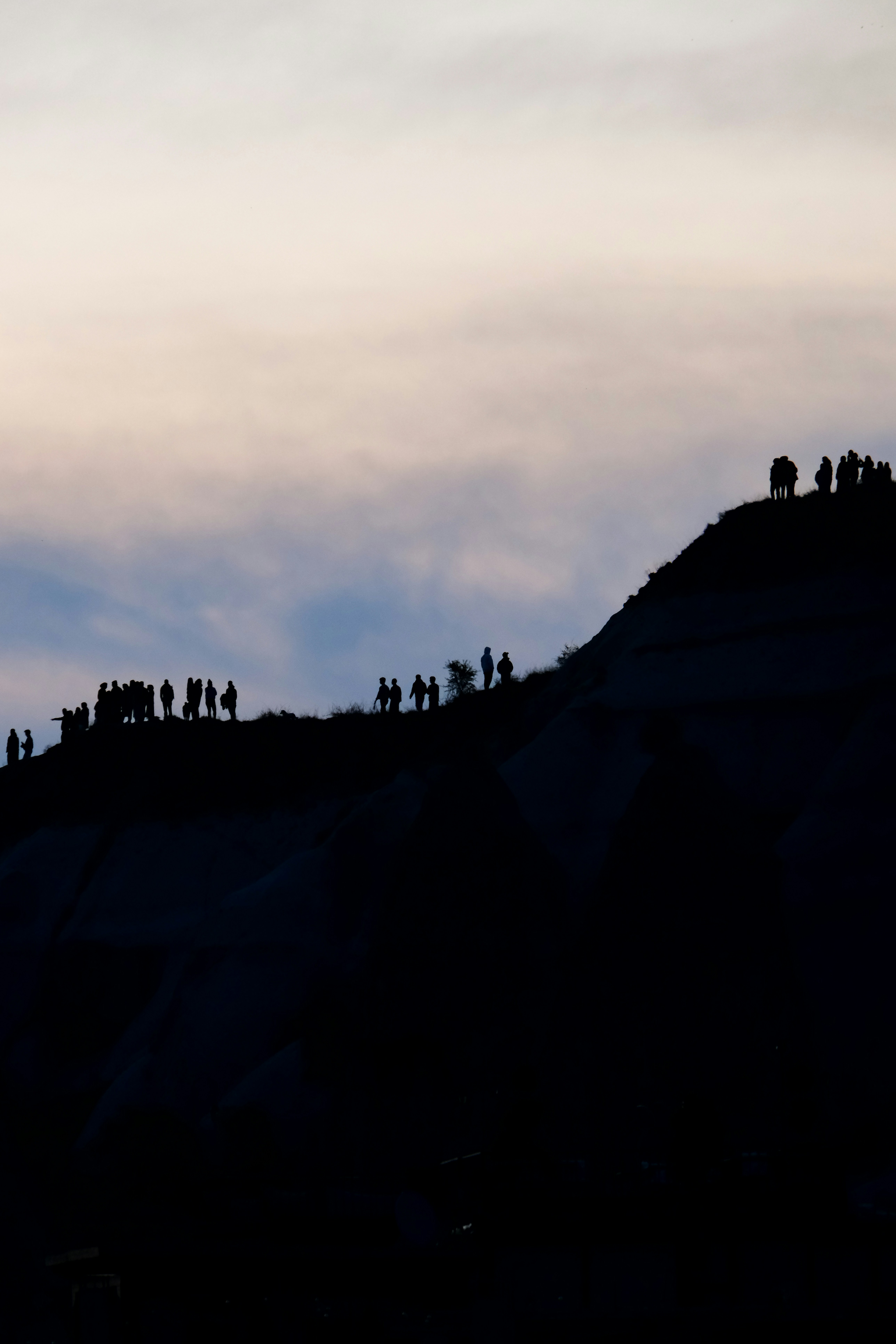 a group of people standing on top of a hill - a-group-of-people-standing-on-top-of-a-hill-Q60oH26Qdx8