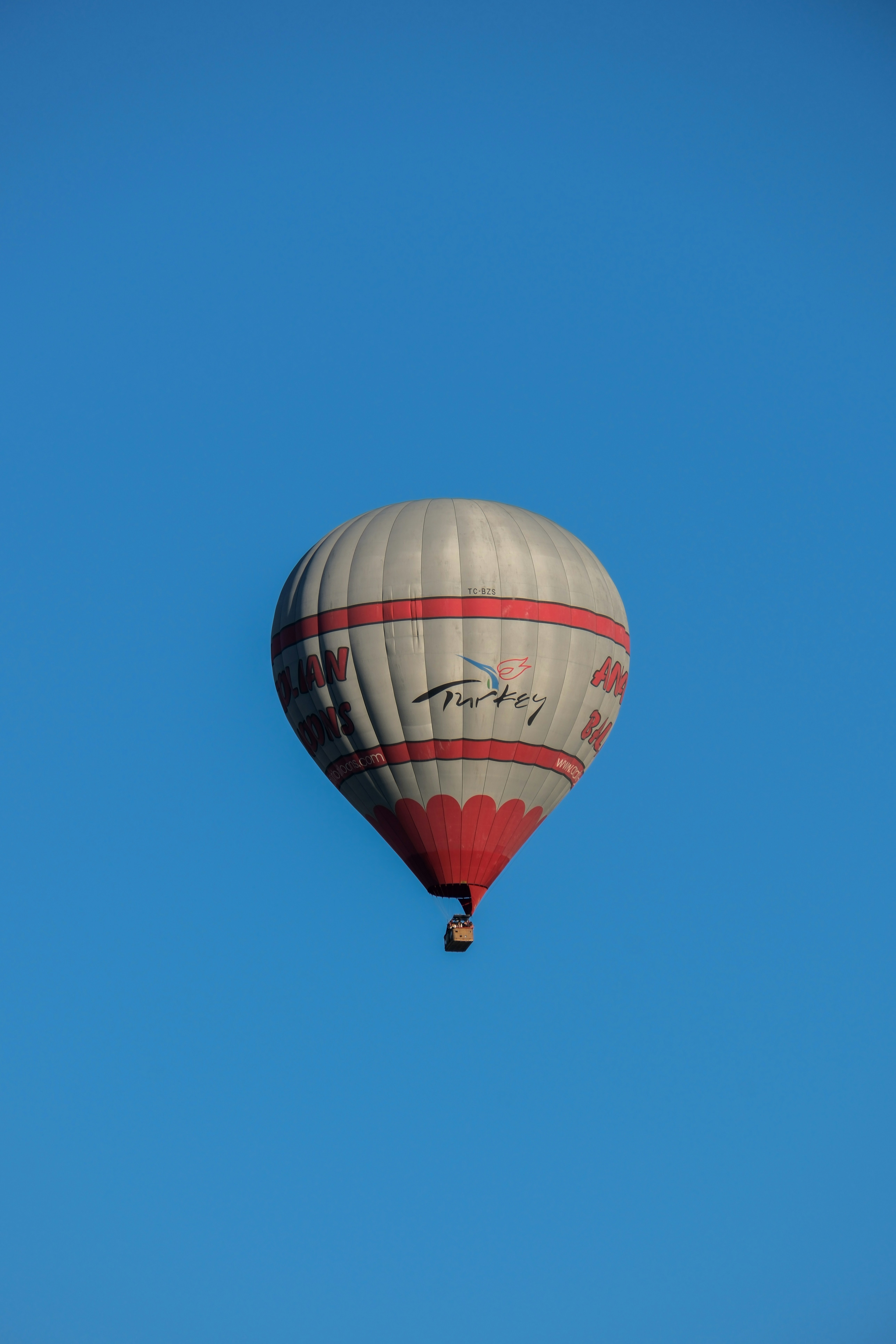 a hot air balloon flying through a blue sky - a-hot-air-balloon-flying-through-a-blue-sky-p9FDmYQUFyE