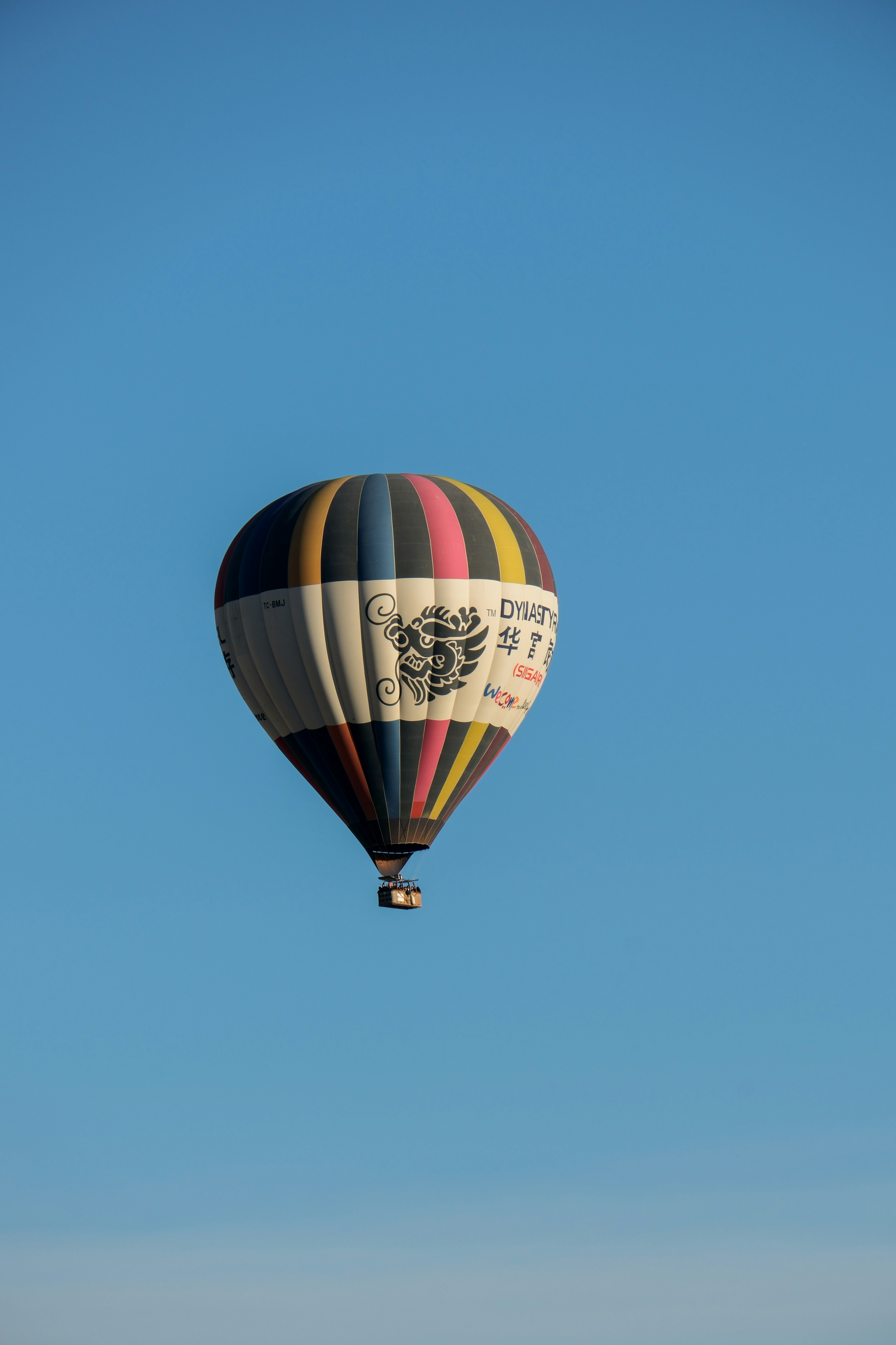 a hot air balloon flying through a blue sky - a-hot-air-balloon-flying-through-a-blue-sky-VA6VRmRKoAE