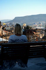 a woman sitting on a bench overlooking a city