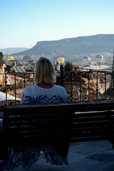 a woman sitting on a bench overlooking a city