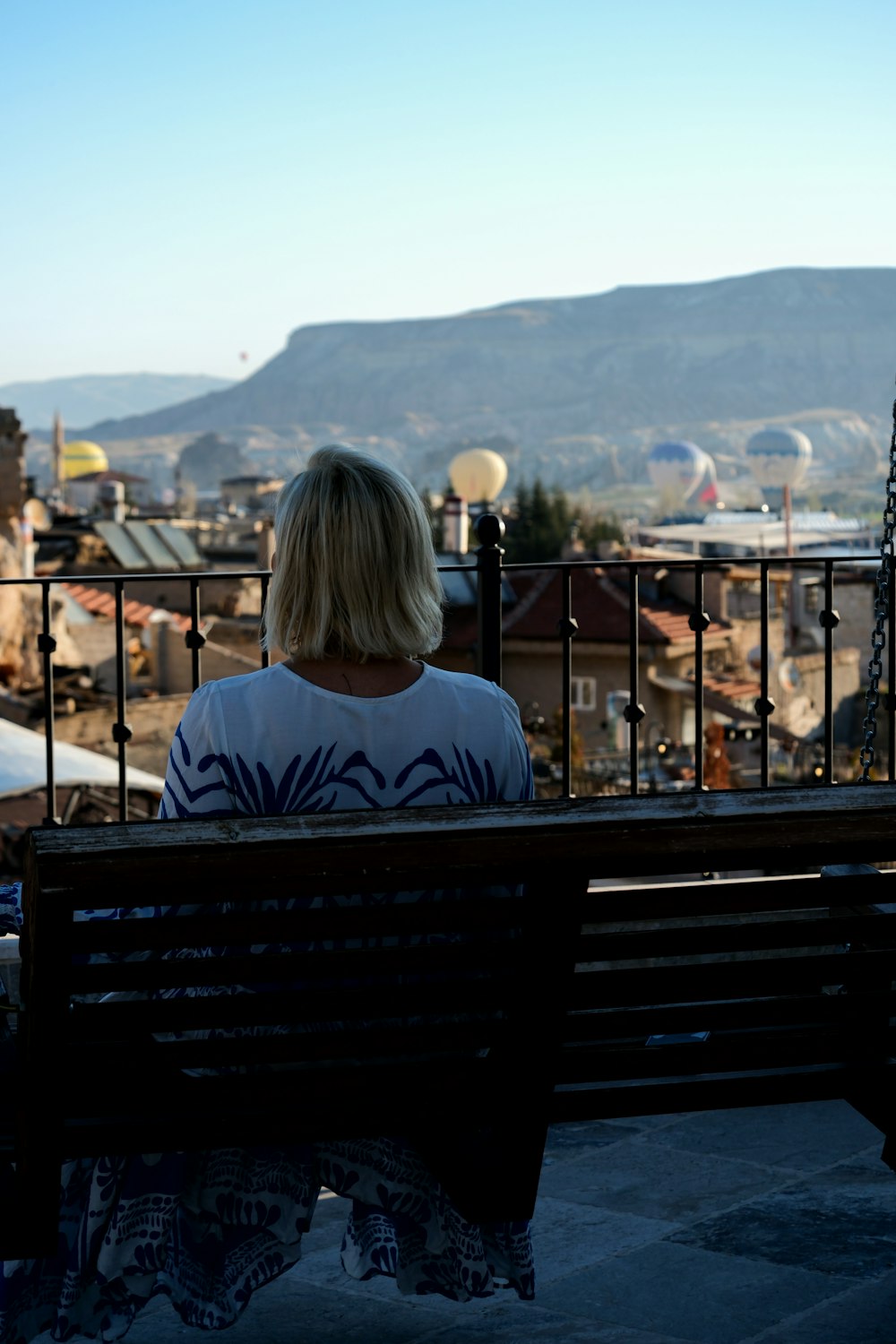 une femme assise sur un banc surplombant une ville