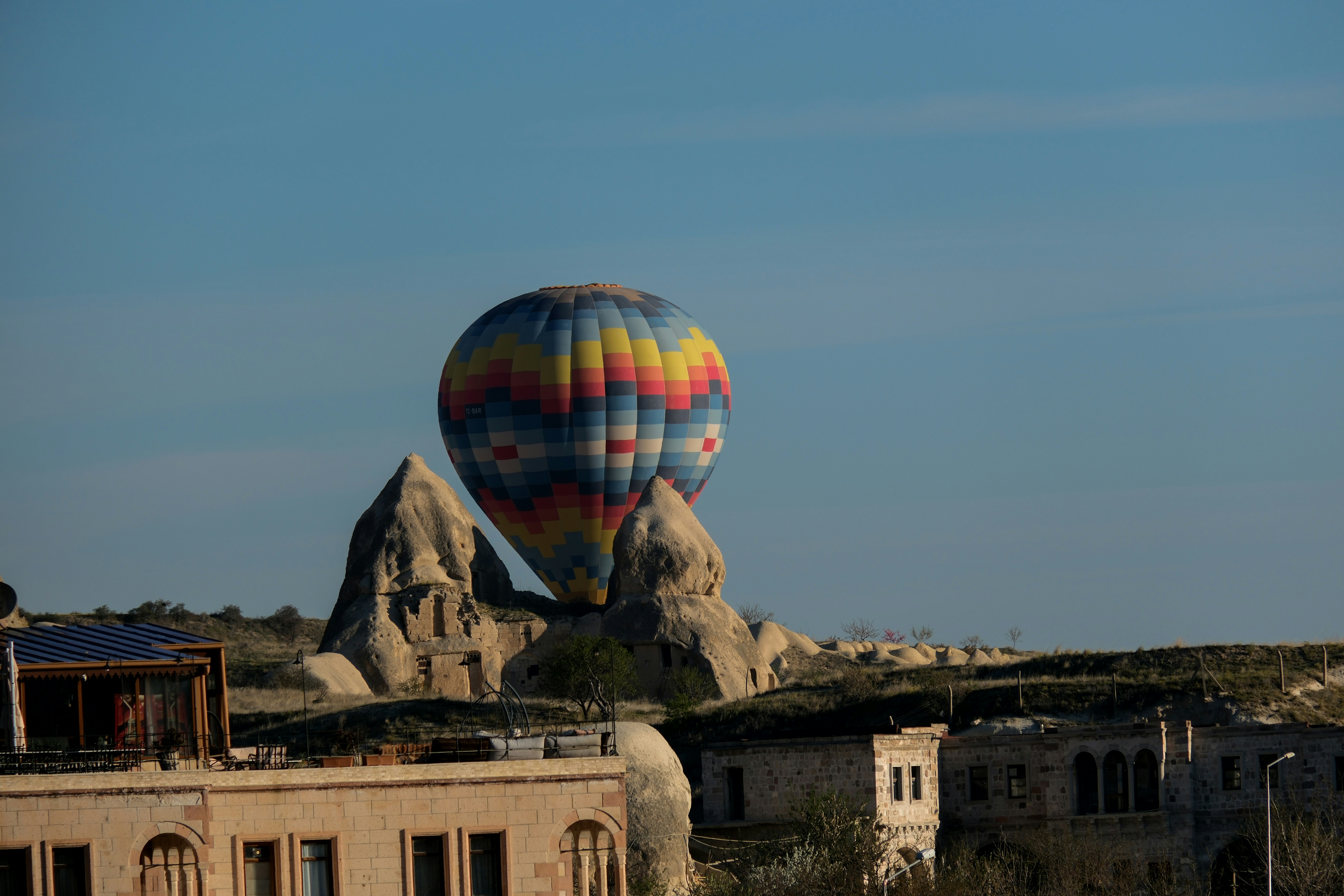 a large hot air balloon flying over a city - a-large-hot-air-balloon-flying-over-a-city-26TEKAG9Flw