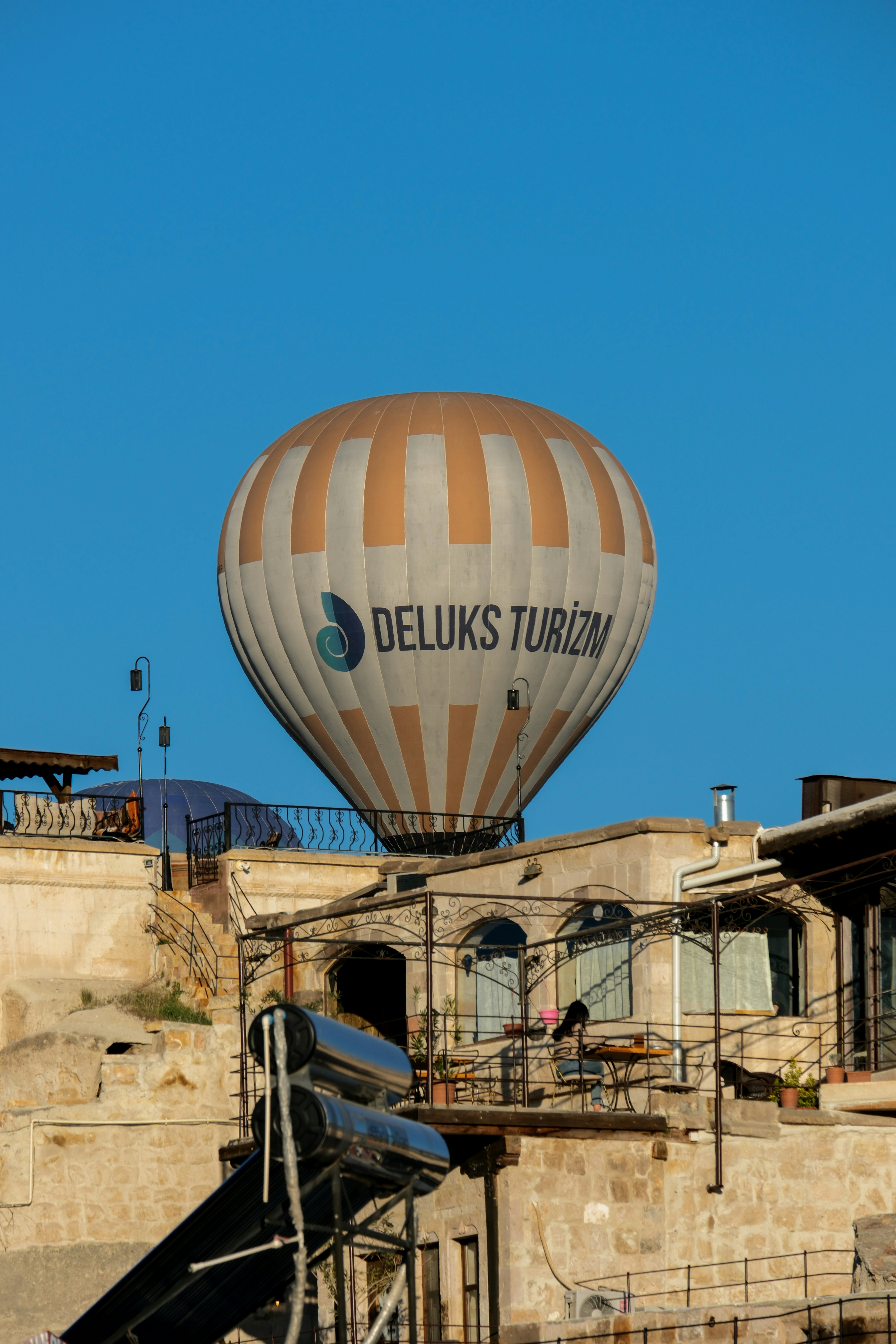 a large hot air balloon flying over a building - a-large-hot-air-balloon-flying-over-a-building-PpNBM0lCRtQ
