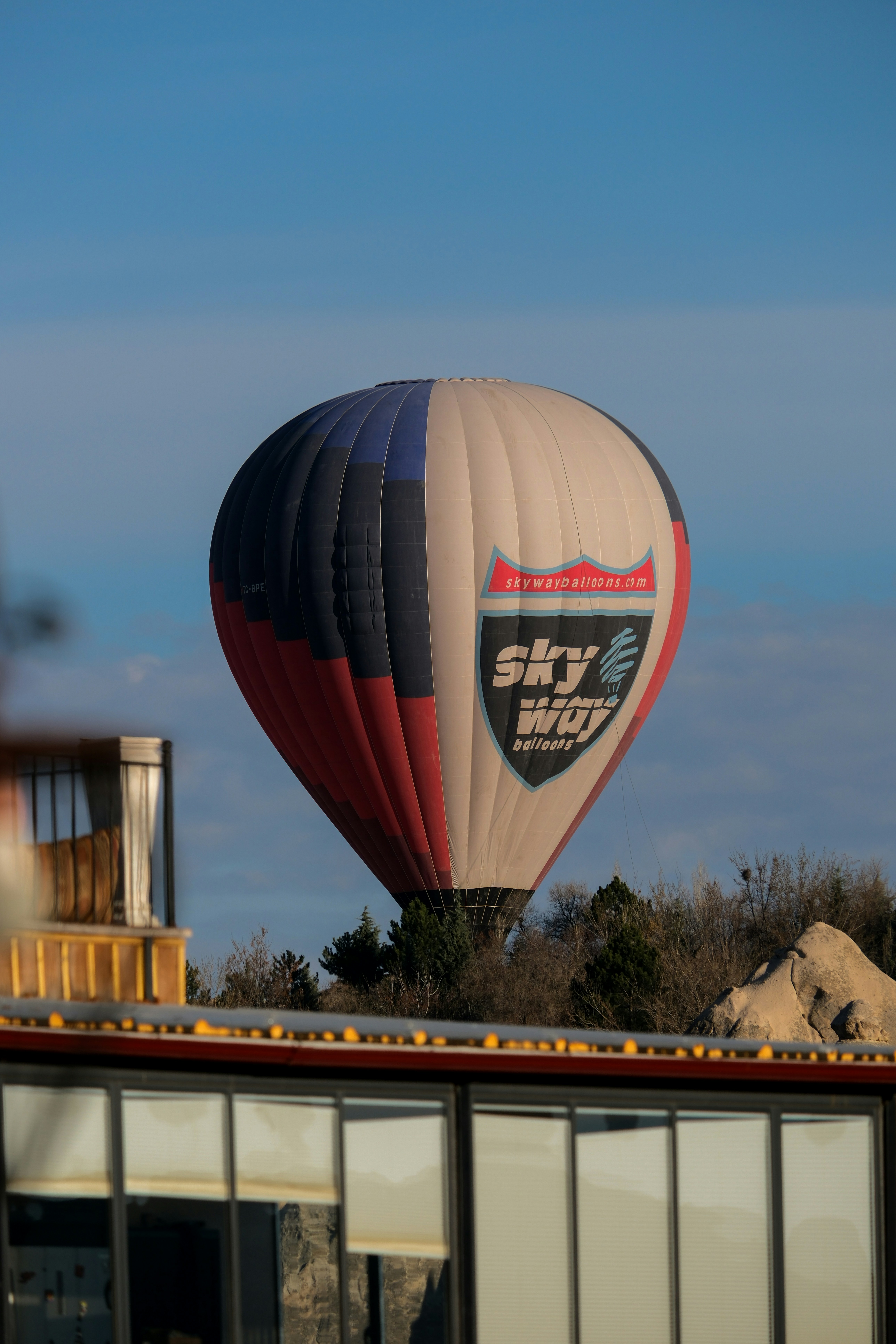 a hot air balloon flying over a building - a-hot-air-balloon-flying-over-a-building-W616XDfvOTc