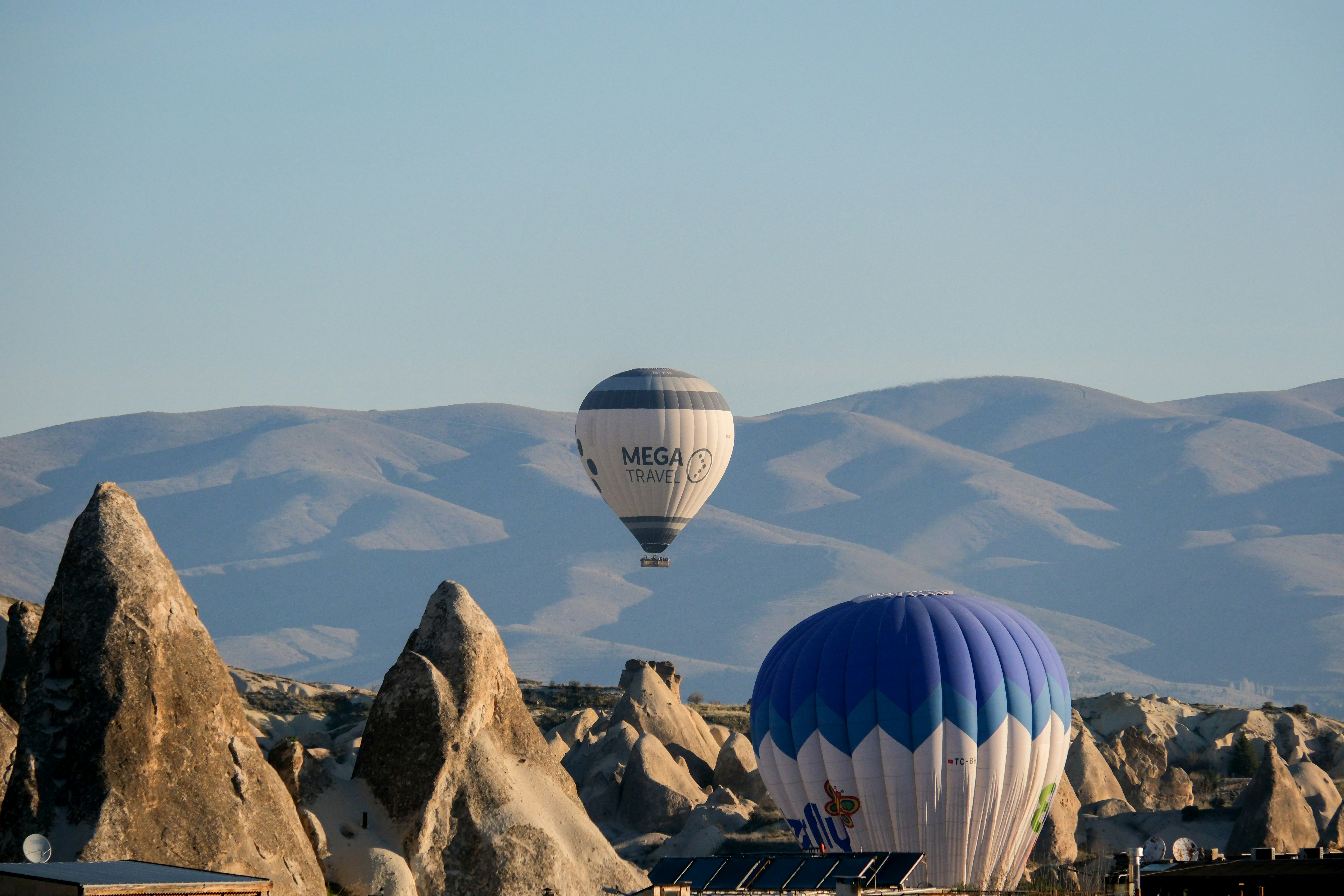 a couple of hot air balloons flying over a mountain - a-couple-of-hot-air-balloons-flying-over-a-mountain-DmwlF5ieTr4