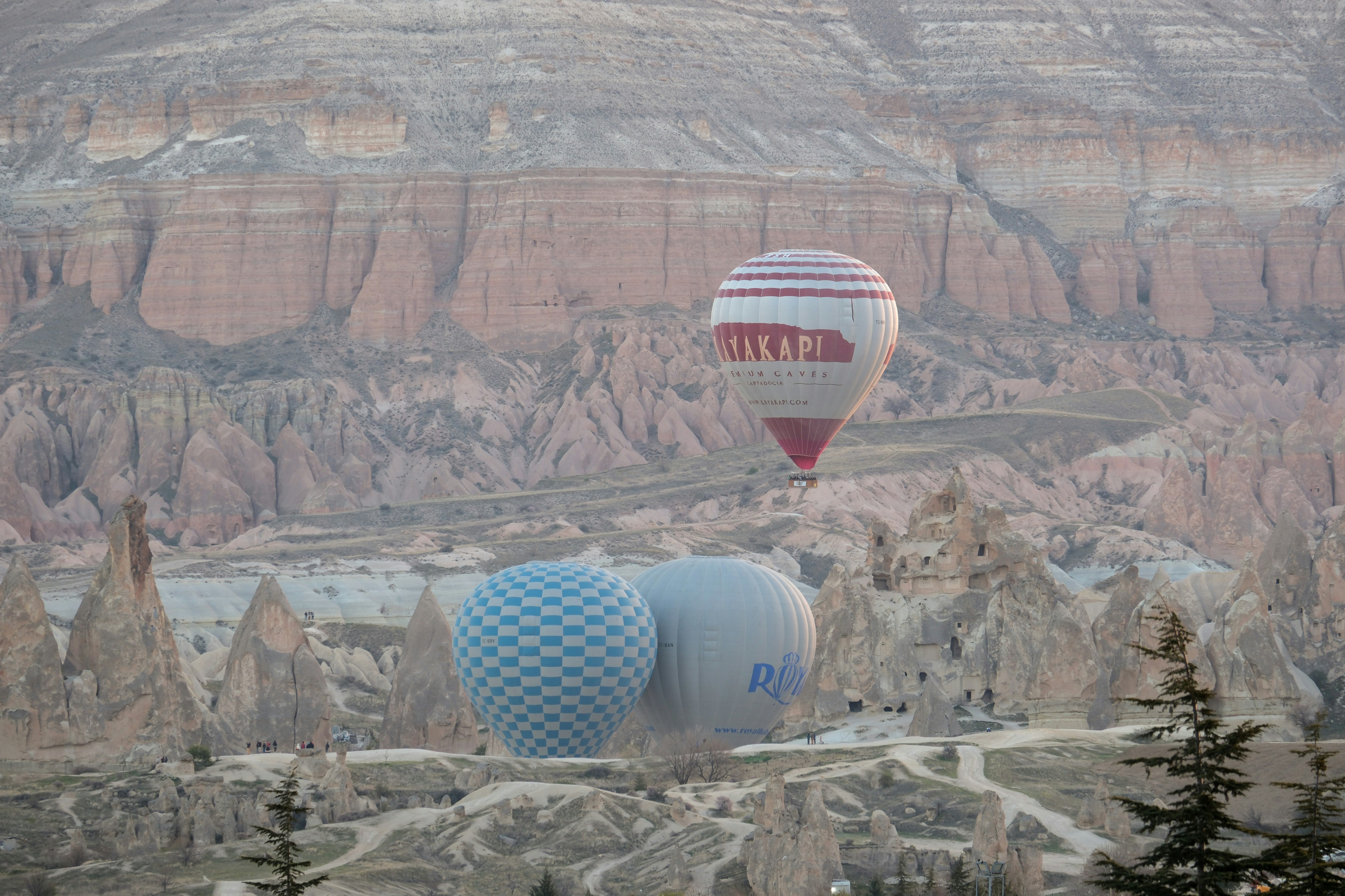 a group of hot air balloons flying over a valley - a-group-of-hot-air-balloons-flying-over-a-valley--0-lUSOWOWs