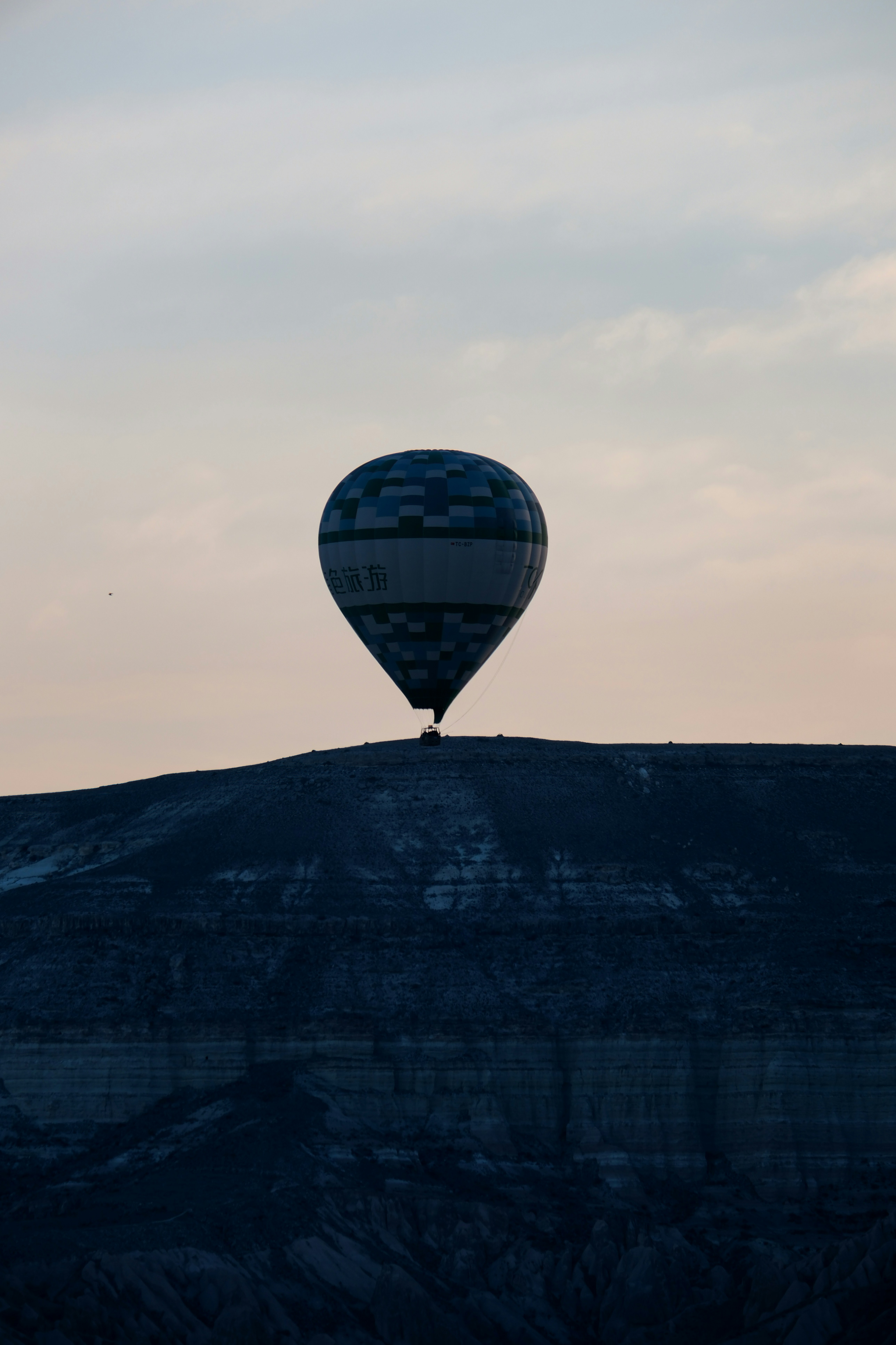 a hot air balloon flying over a mountain - a-hot-air-balloon-flying-over-a-mountain-C-HLhHeH7hM
