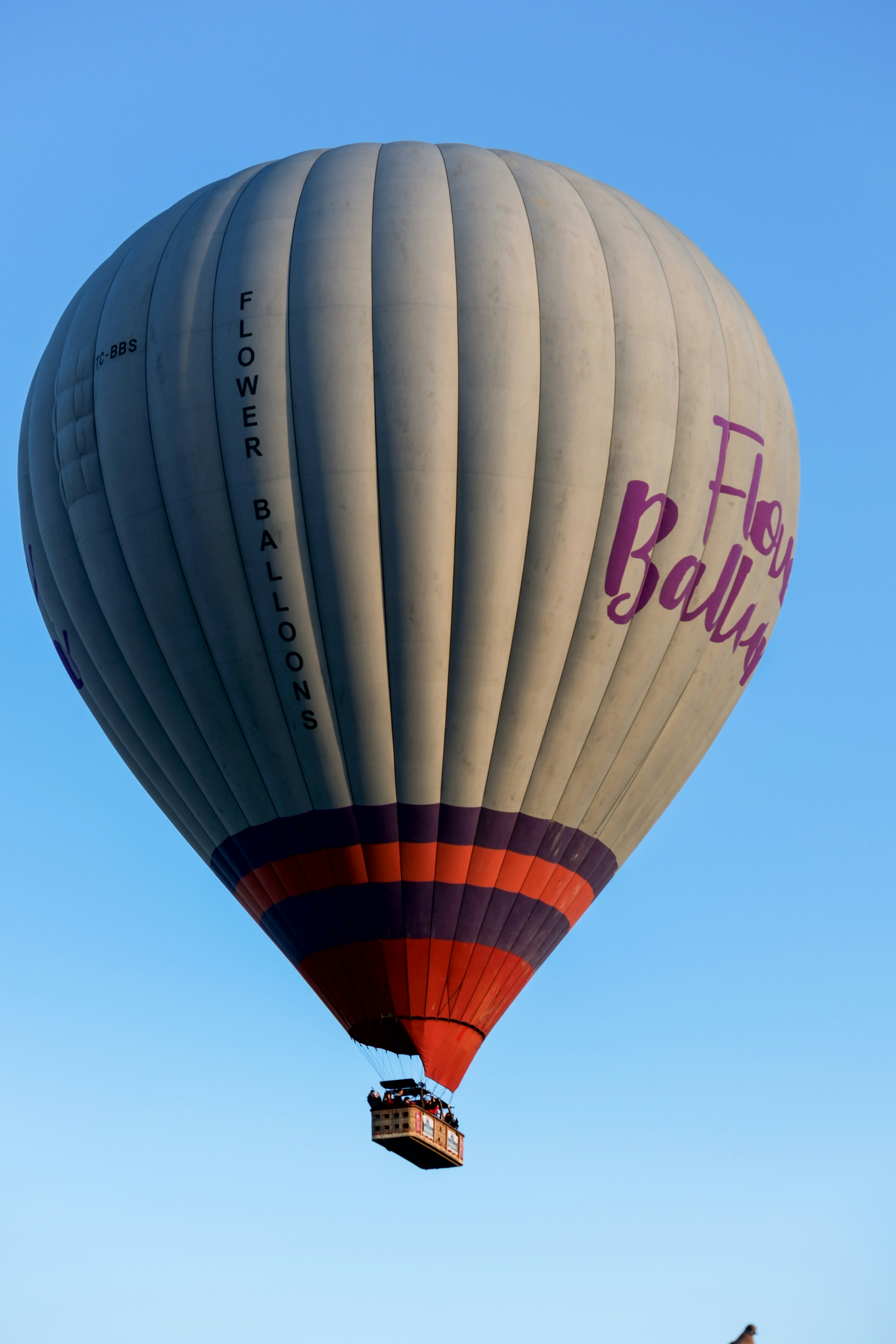 a large hot air balloon flying through a blue sky - a-large-hot-air-balloon-flying-through-a-blue-sky-pz8XVQZqPtA