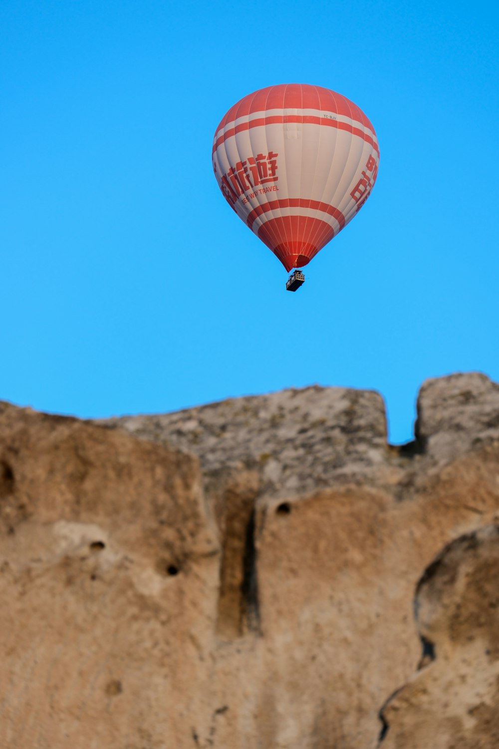 a hot air balloon flying over a rocky cliff
