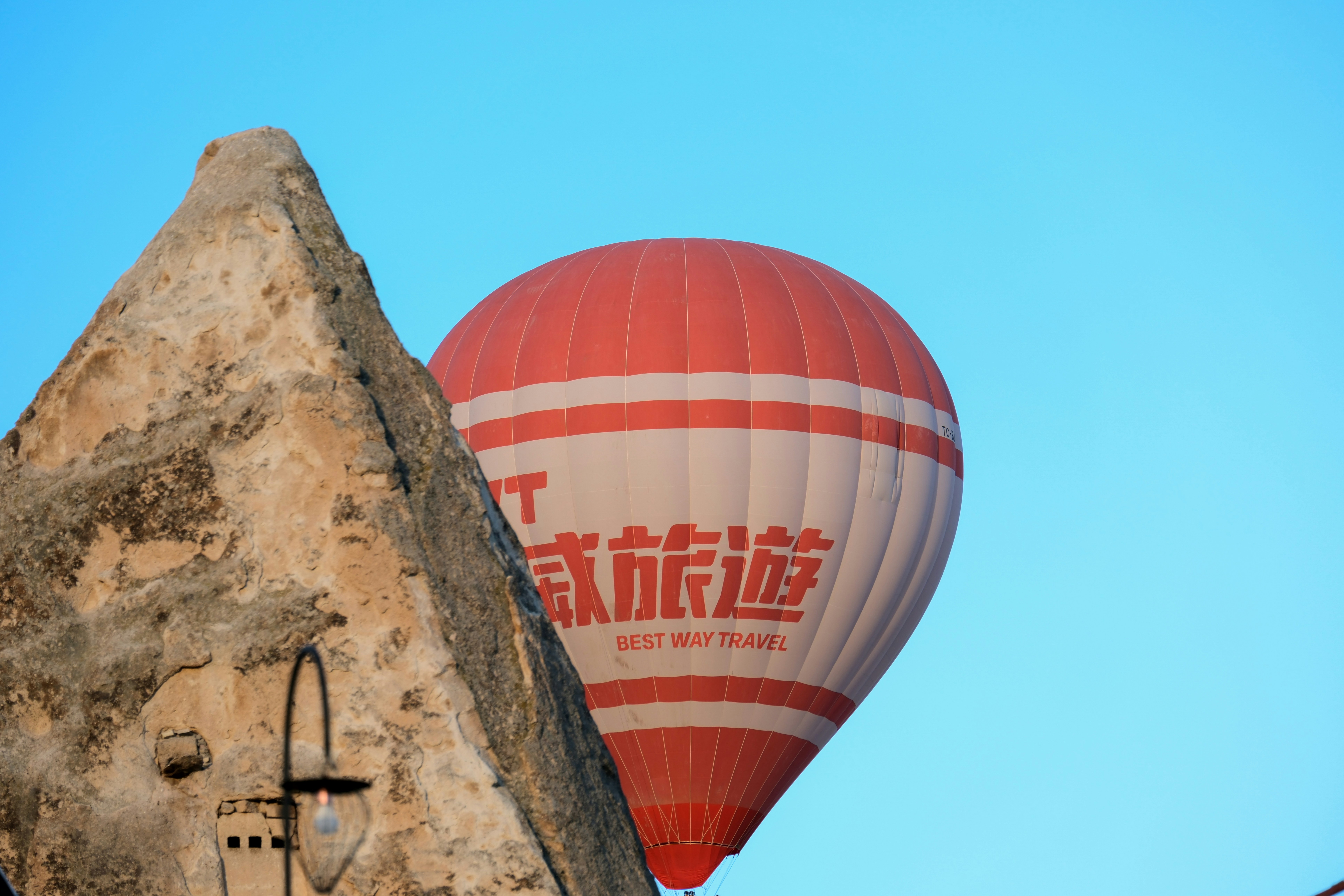 a hot air balloon flying over a stone building - a-hot-air-balloon-flying-over-a-stone-building-YfqzhujiP80