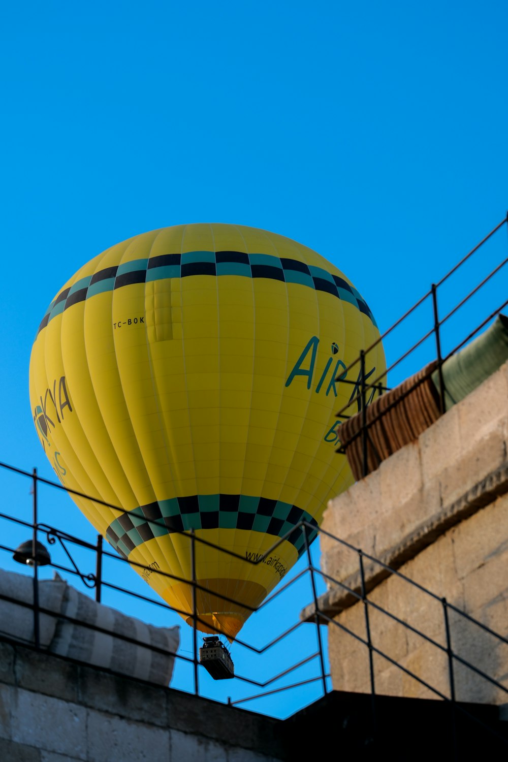 a large yellow hot air balloon flying over a building