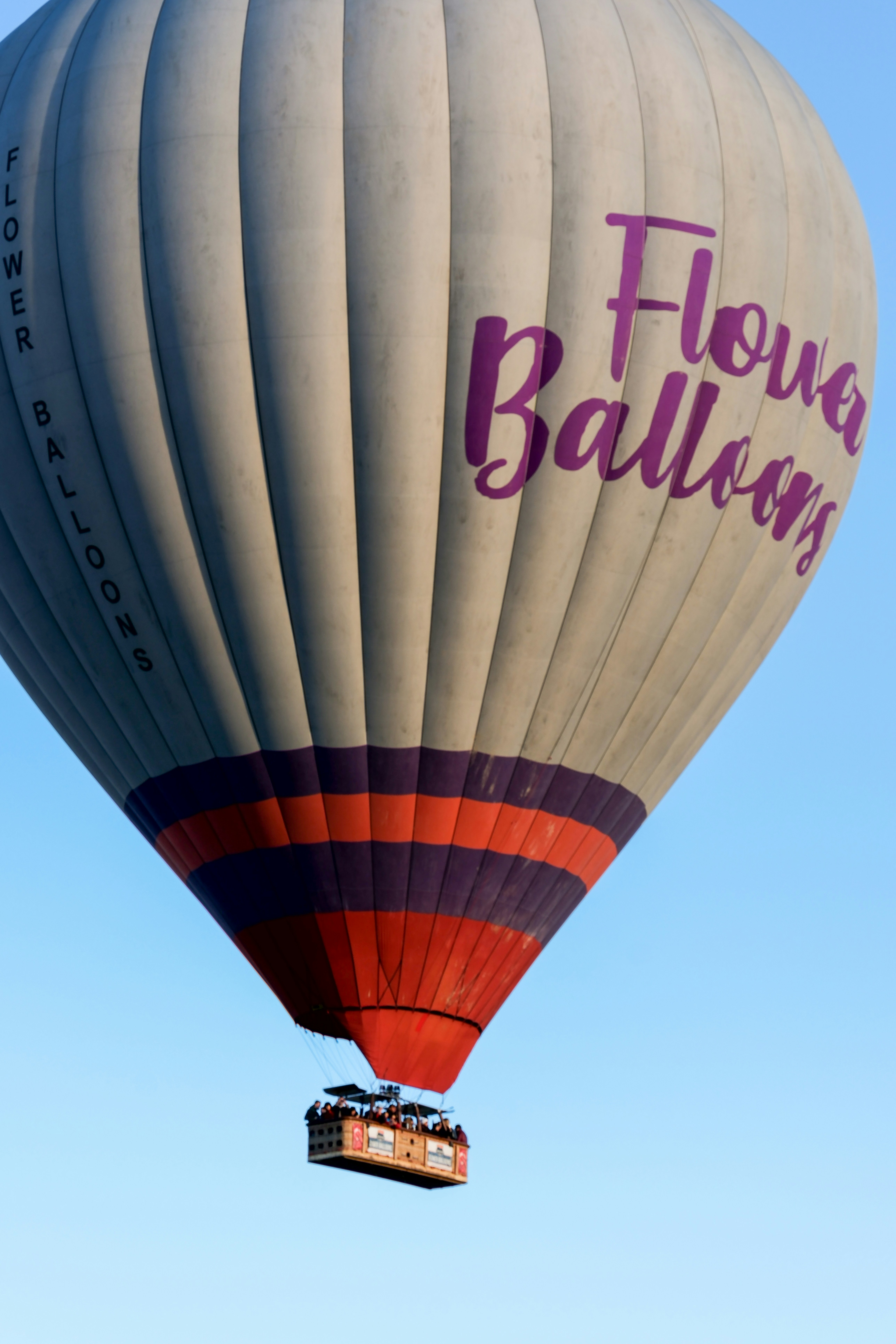 a large hot air balloon flying through a blue sky - a-large-hot-air-balloon-flying-through-a-blue-sky-sGj0aH8Y9Eo