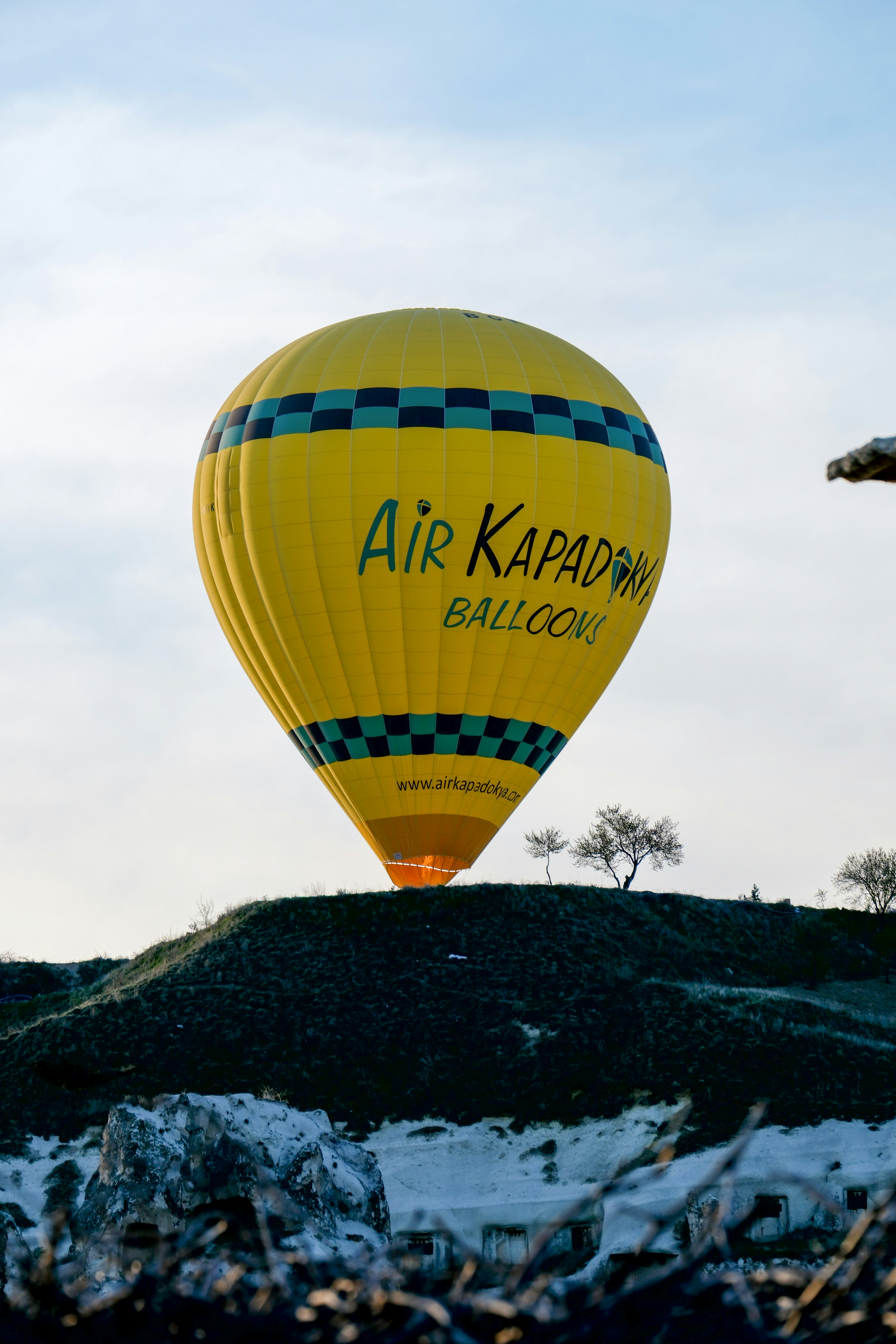 a hot air balloon flying over a snow covered hill - a-hot-air-balloon-flying-over-a-snow-covered-hill-j-G_u59gMI0