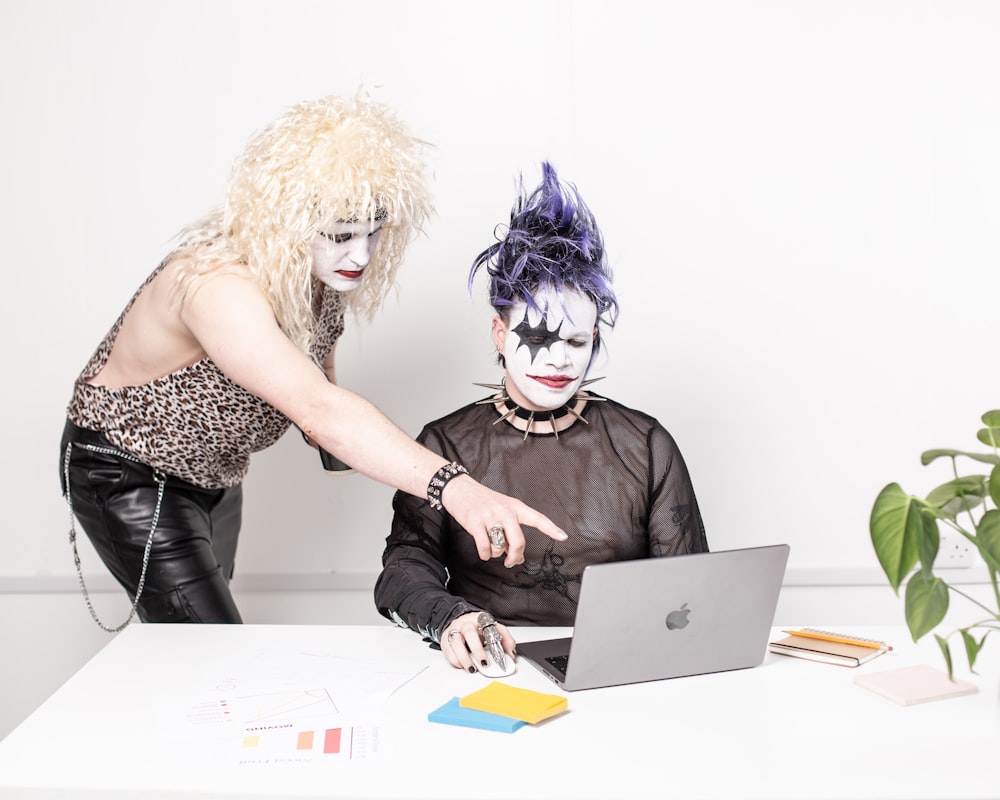 two people dressed up as clowns working on a laptop