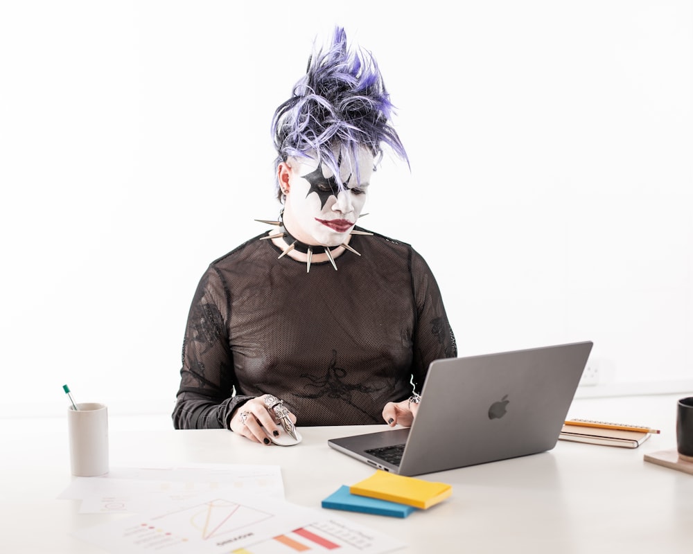 a person in a cat mask sitting in front of a laptop