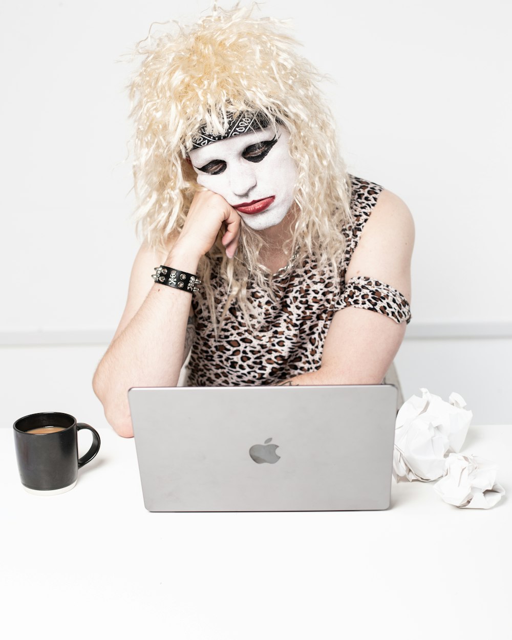a woman in a mask sitting in front of a laptop