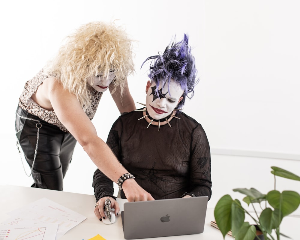 two women dressed as clowns working on a laptop