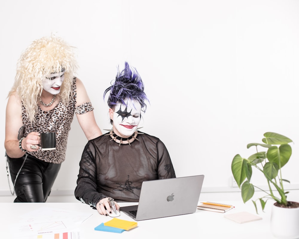 two women dressed as clowns working on a laptop