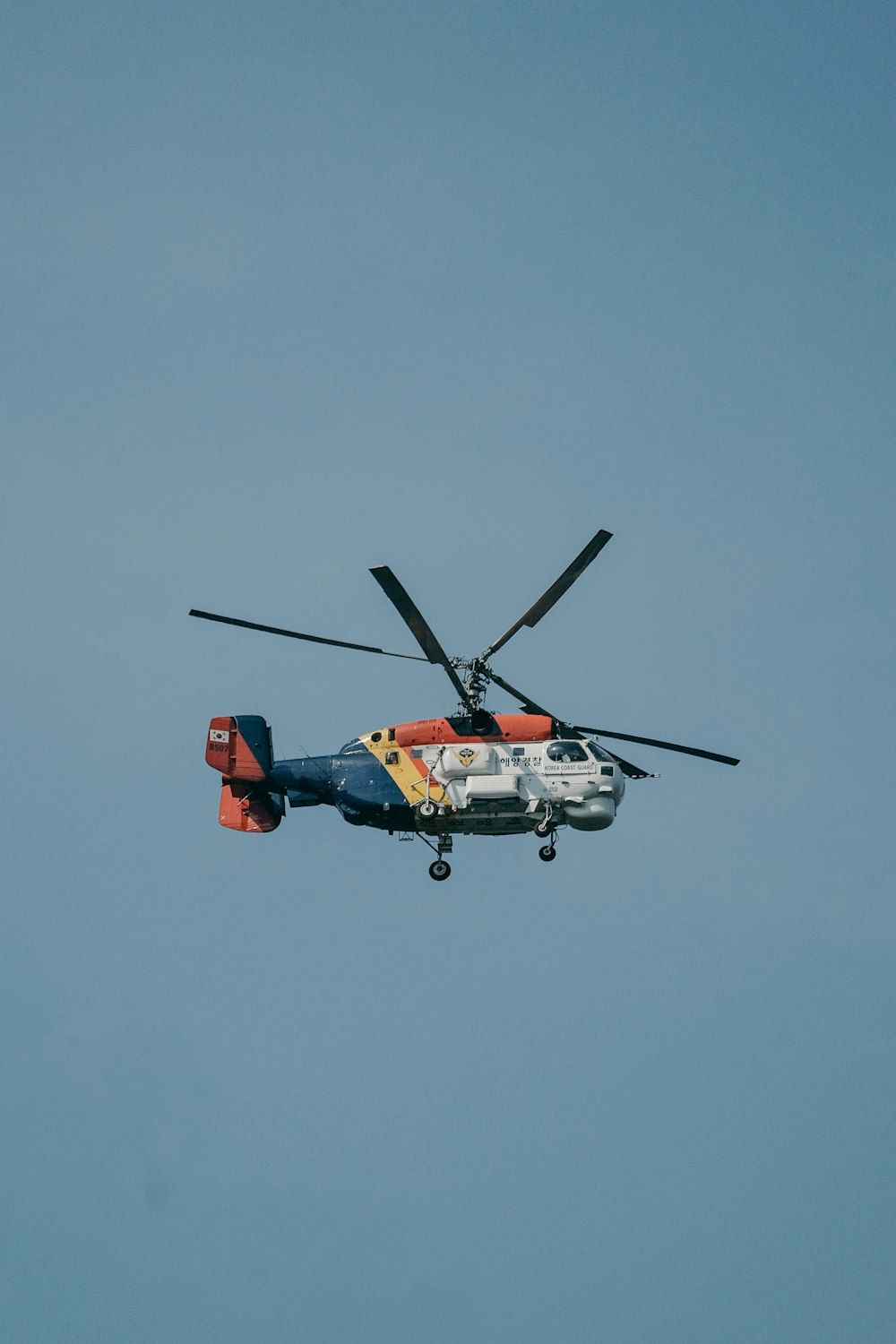 Ein Hubschrauber, der mit Propellern durch einen blauen Himmel fliegt
