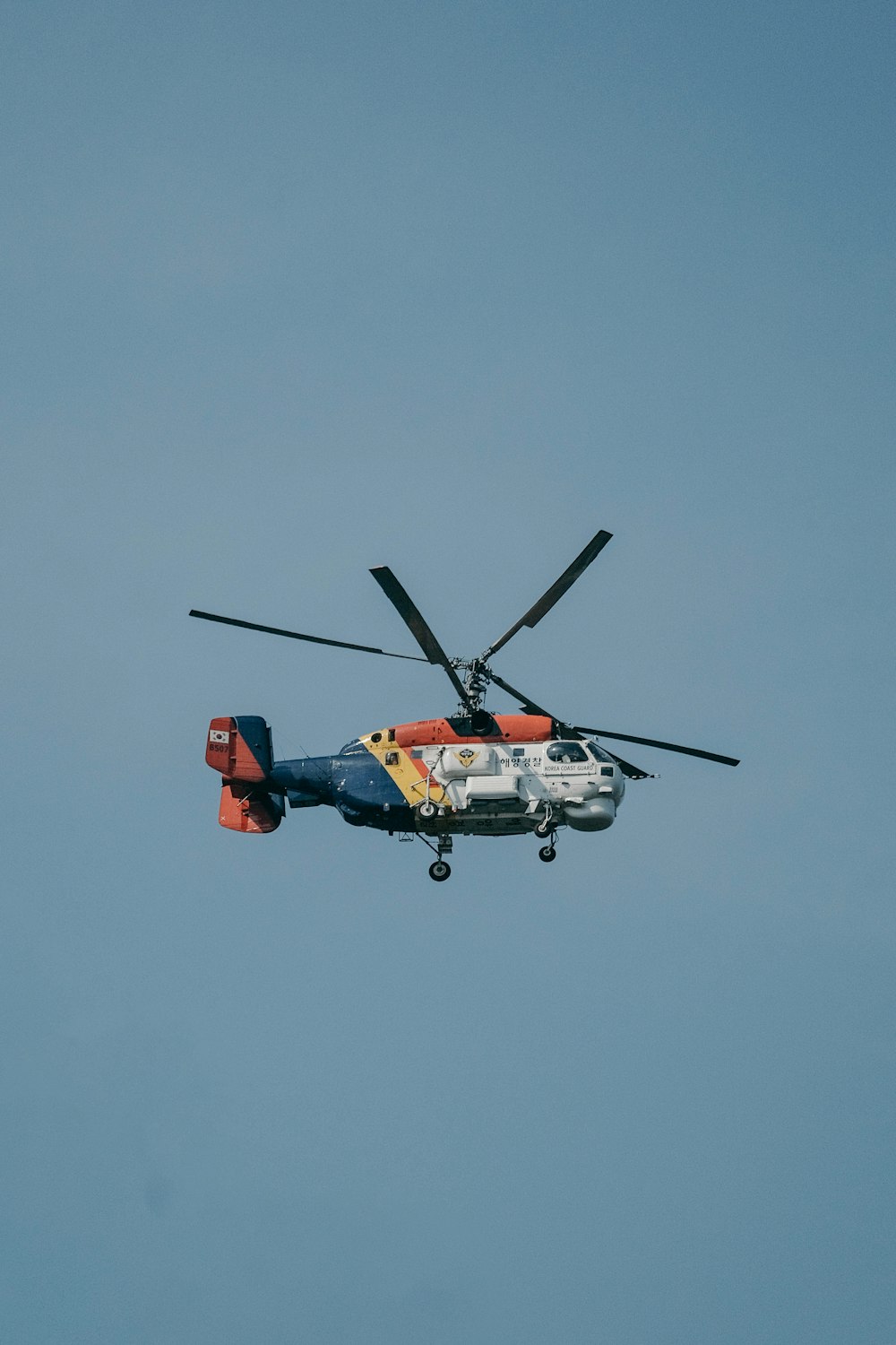 a helicopter flying through a blue sky with propellers