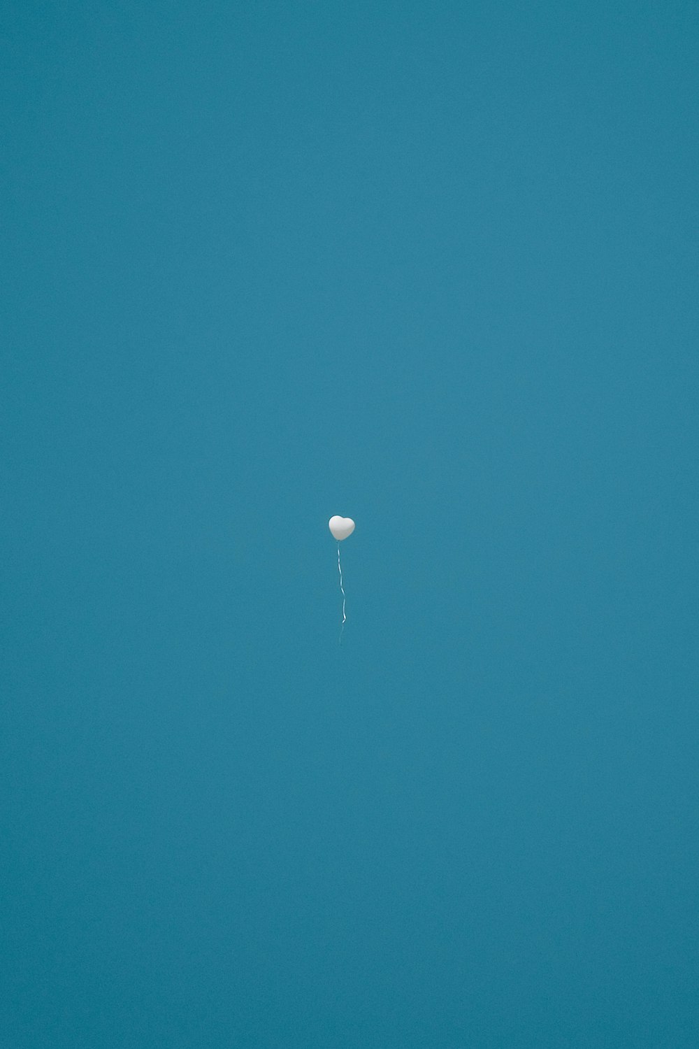 a white balloon floating in a blue sky