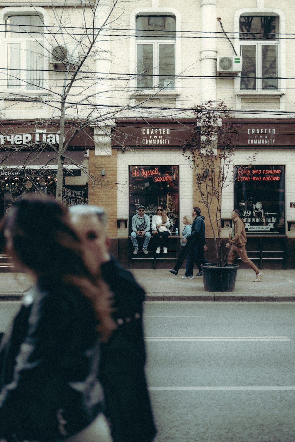 a group of people walking down a street next to a tall building