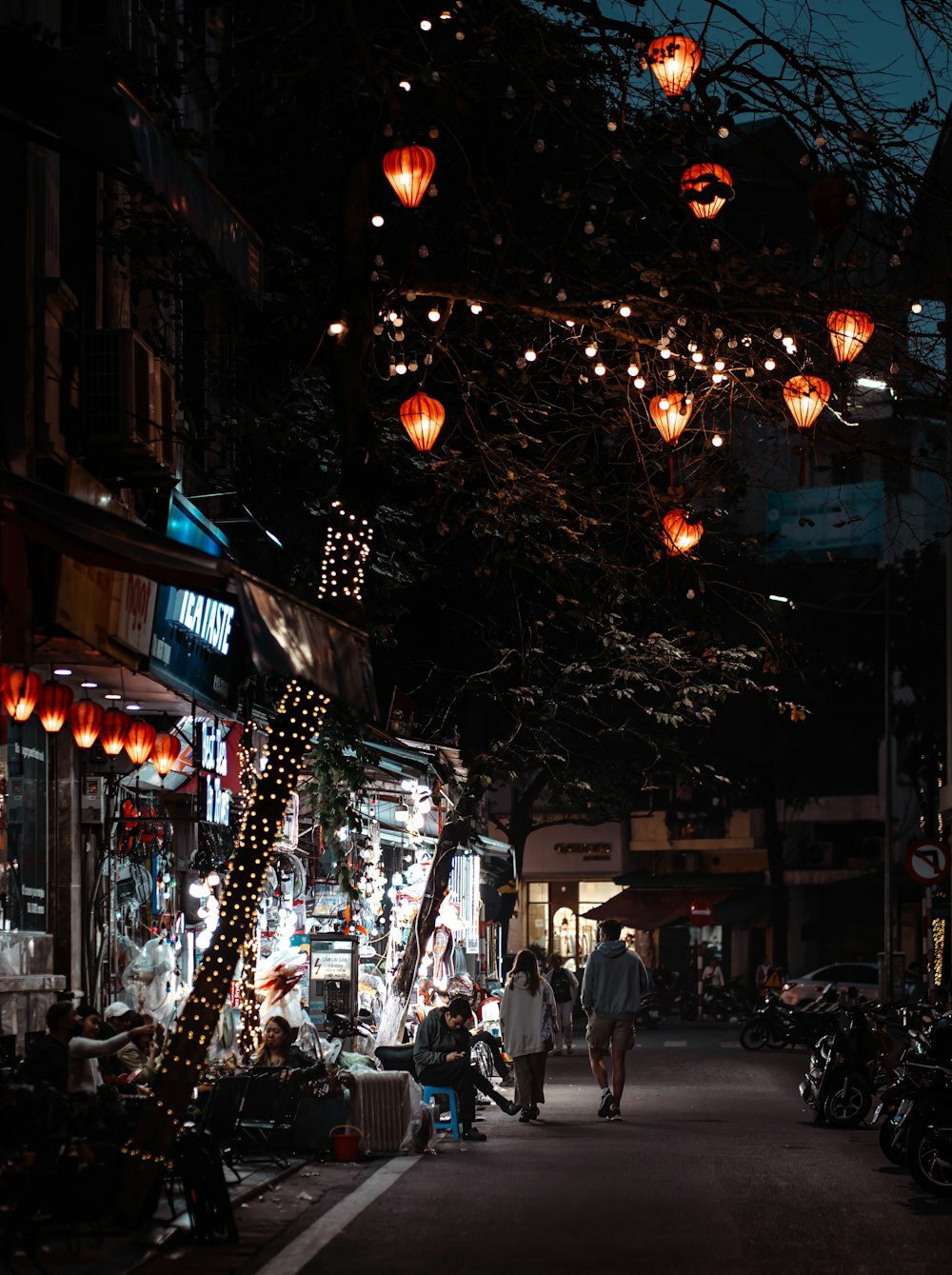 a dark street with lots of lights hanging from the ceiling
