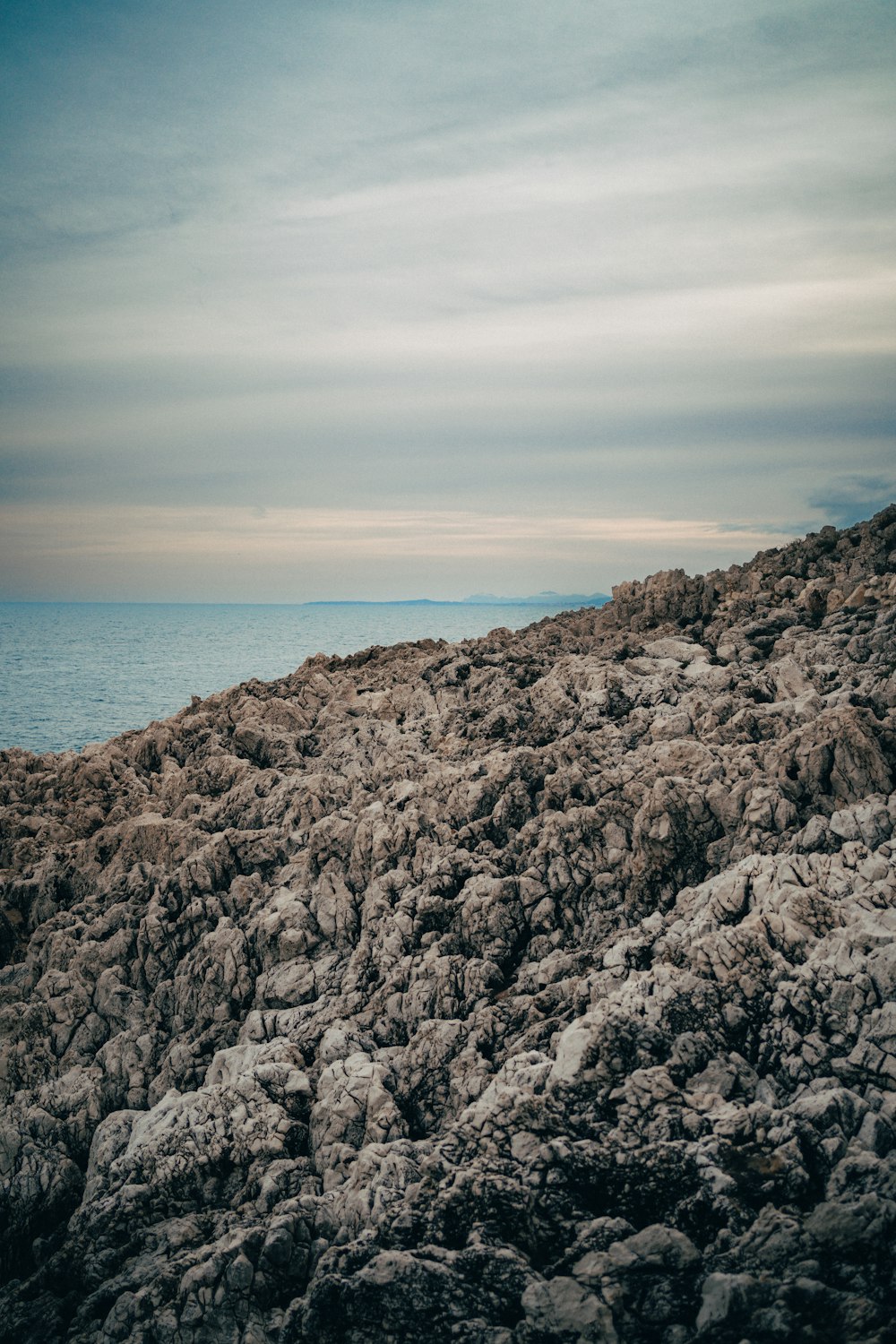 a person standing on top of a rocky hill next to the ocean