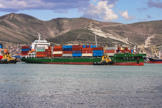 a large cargo ship in the water with mountains in the background