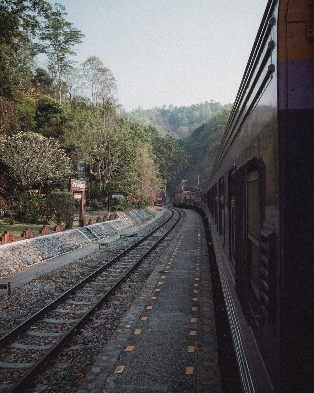 a train traveling down train tracks next to a forest