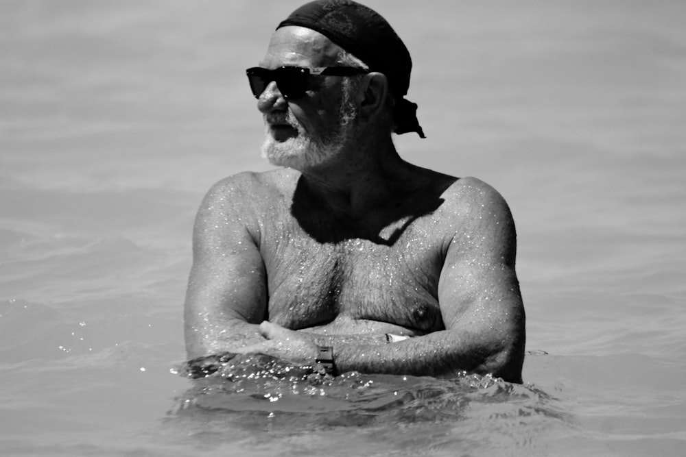 a man in the water wearing a hat and sunglasses