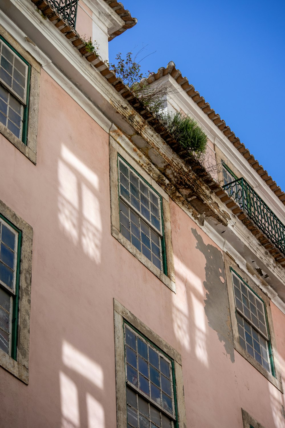 a pink building with green windows and a balcony