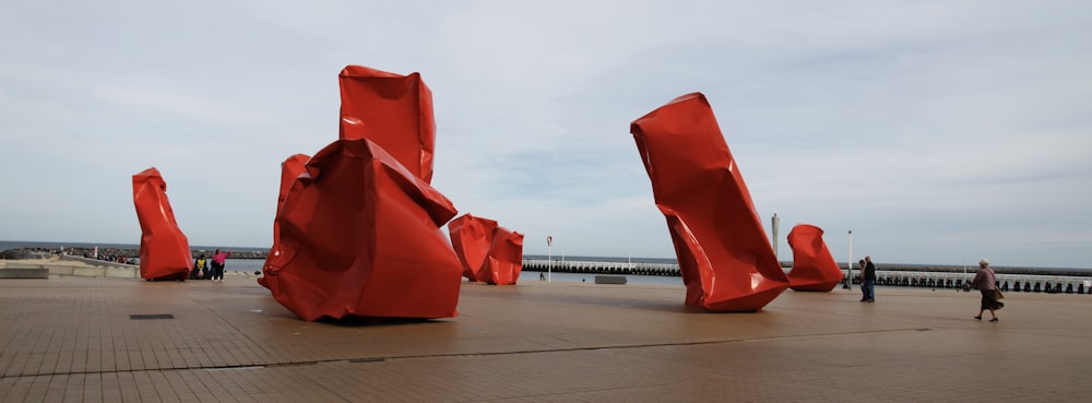 un gruppo di sculture rosse sedute in cima a un marciapiede