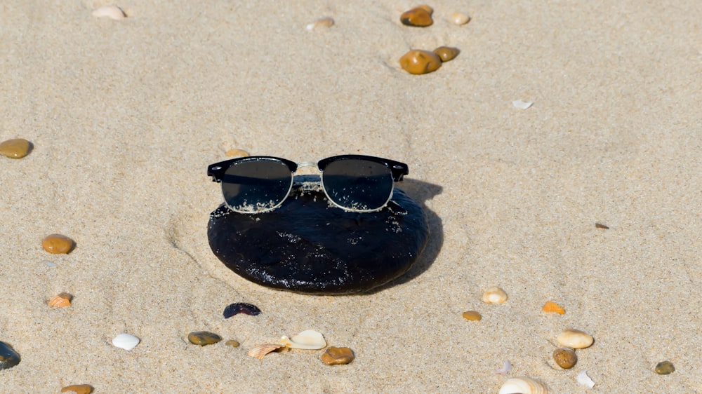a pair of sunglasses sitting on top of a rock in the sand