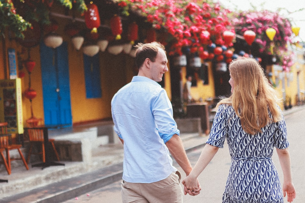 a man and a woman walking down a street holding hands