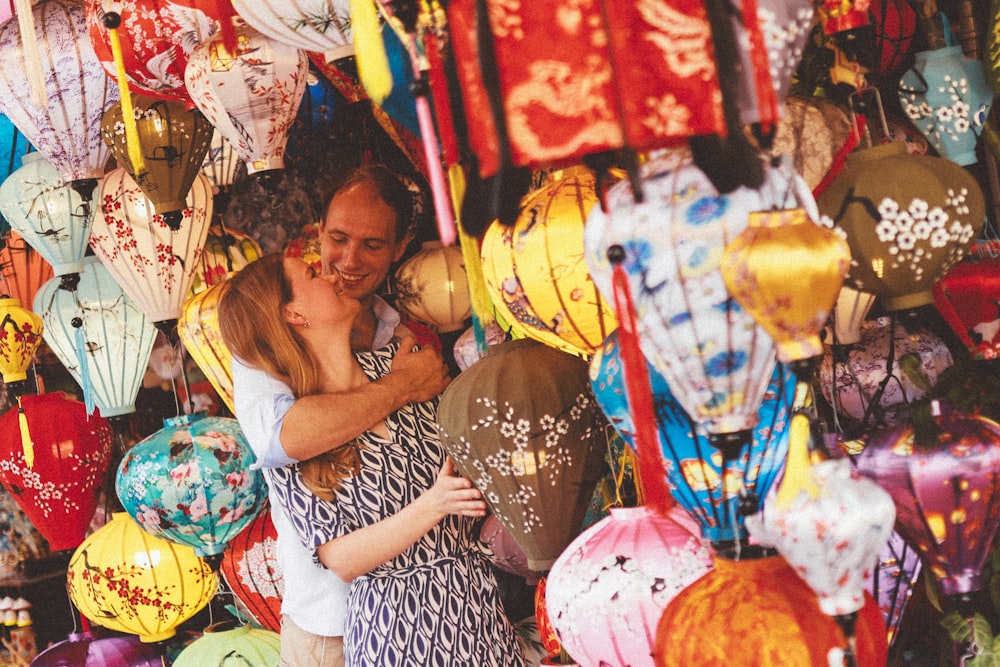 a man and a woman embracing in front of a display of colorful paper lanterns