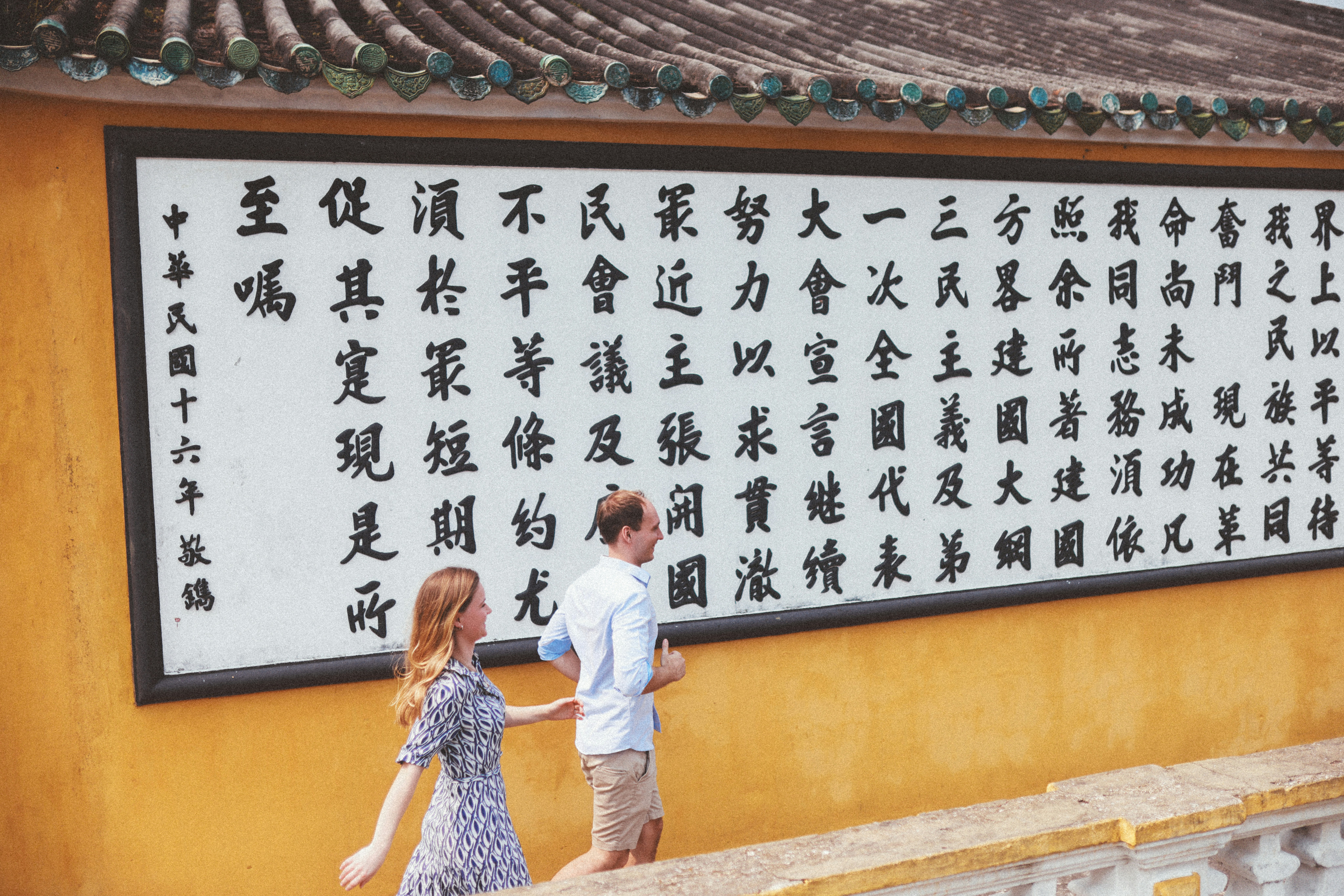 a man and a woman walking in front of a sign