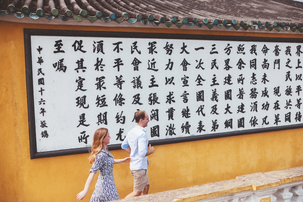 a man and a woman walking in front of a sign