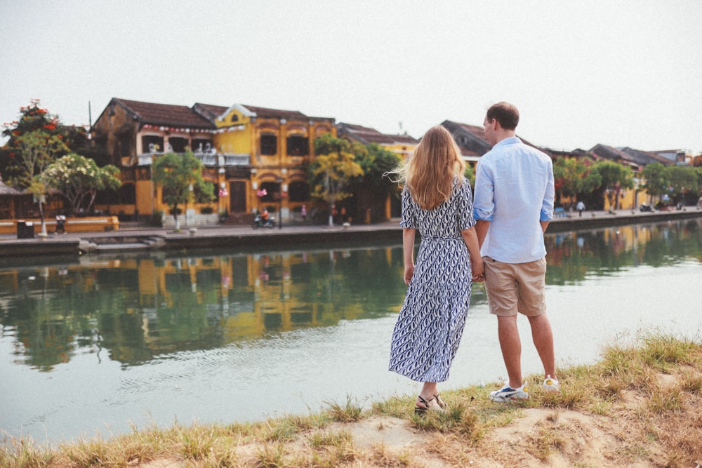 a man and a woman standing next to a body of water