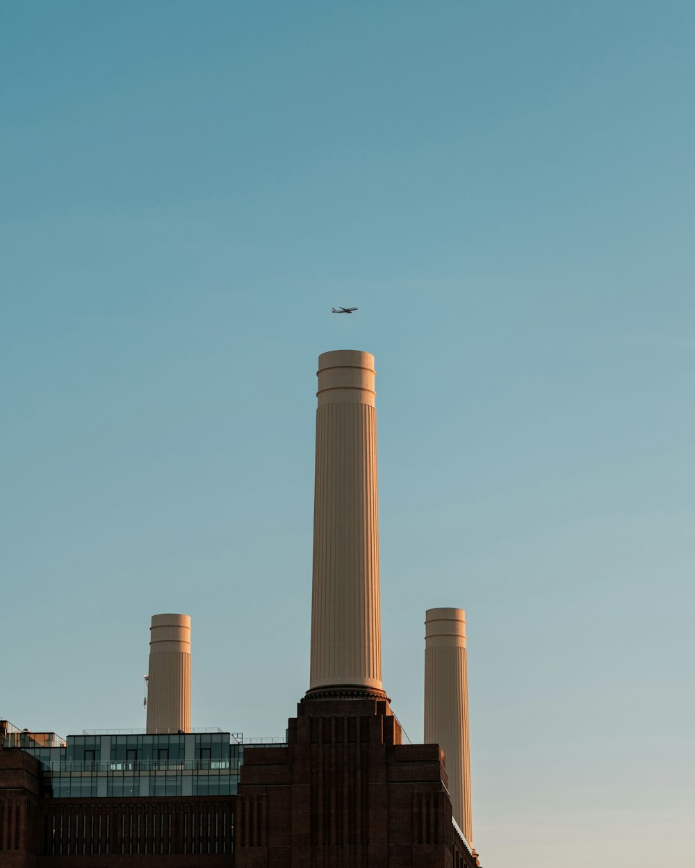 an airplane is flying over a building with chimneys