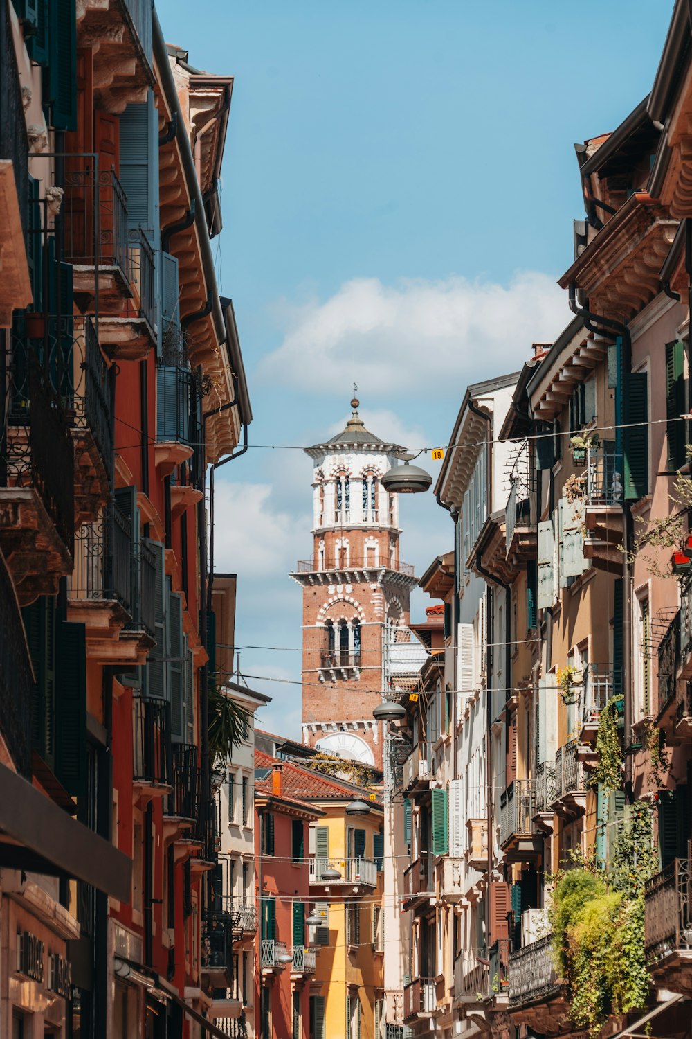 a narrow city street with a clock tower in the background