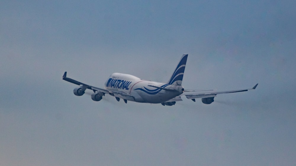 un gran avión de pasajeros volando a través de un cielo azul nublado