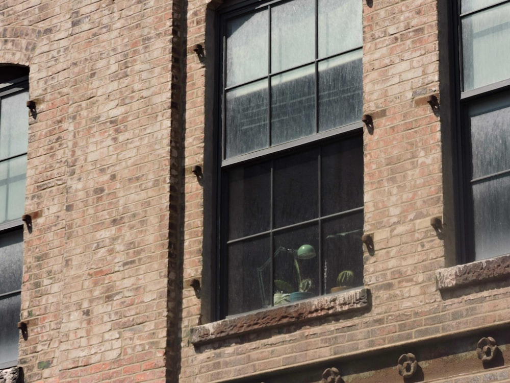 a brick building with two windows and a person looking out the window