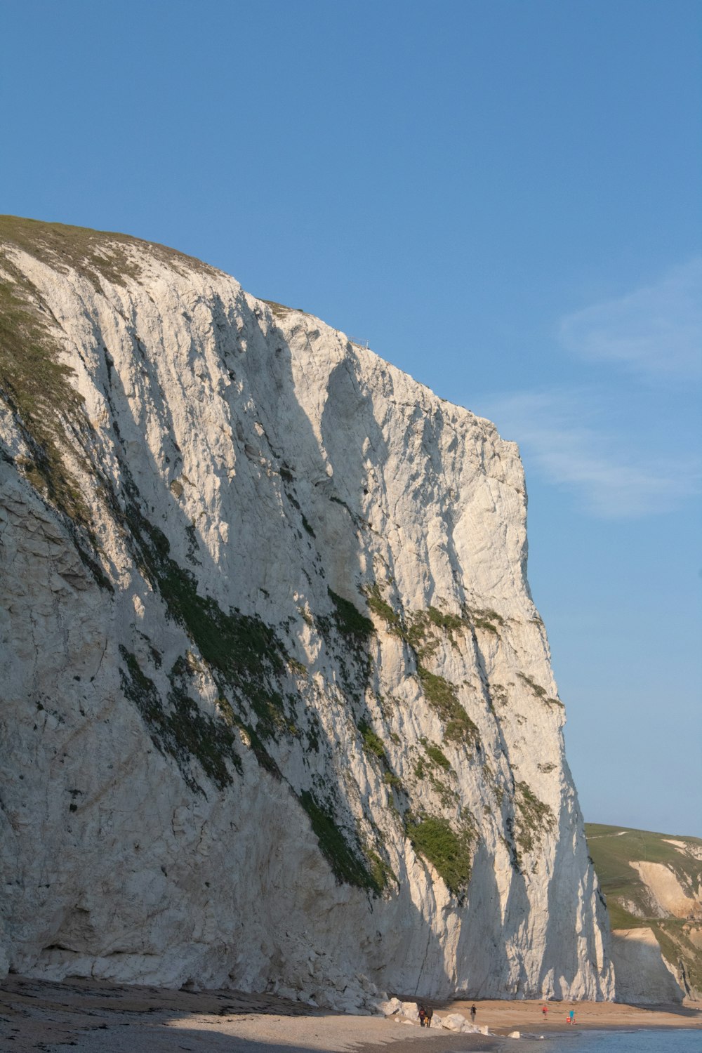 a large white cliff next to a body of water